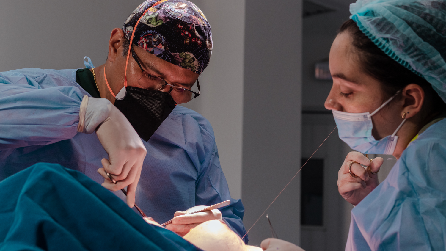 Medical professionals in protective gear working together during surgery.
