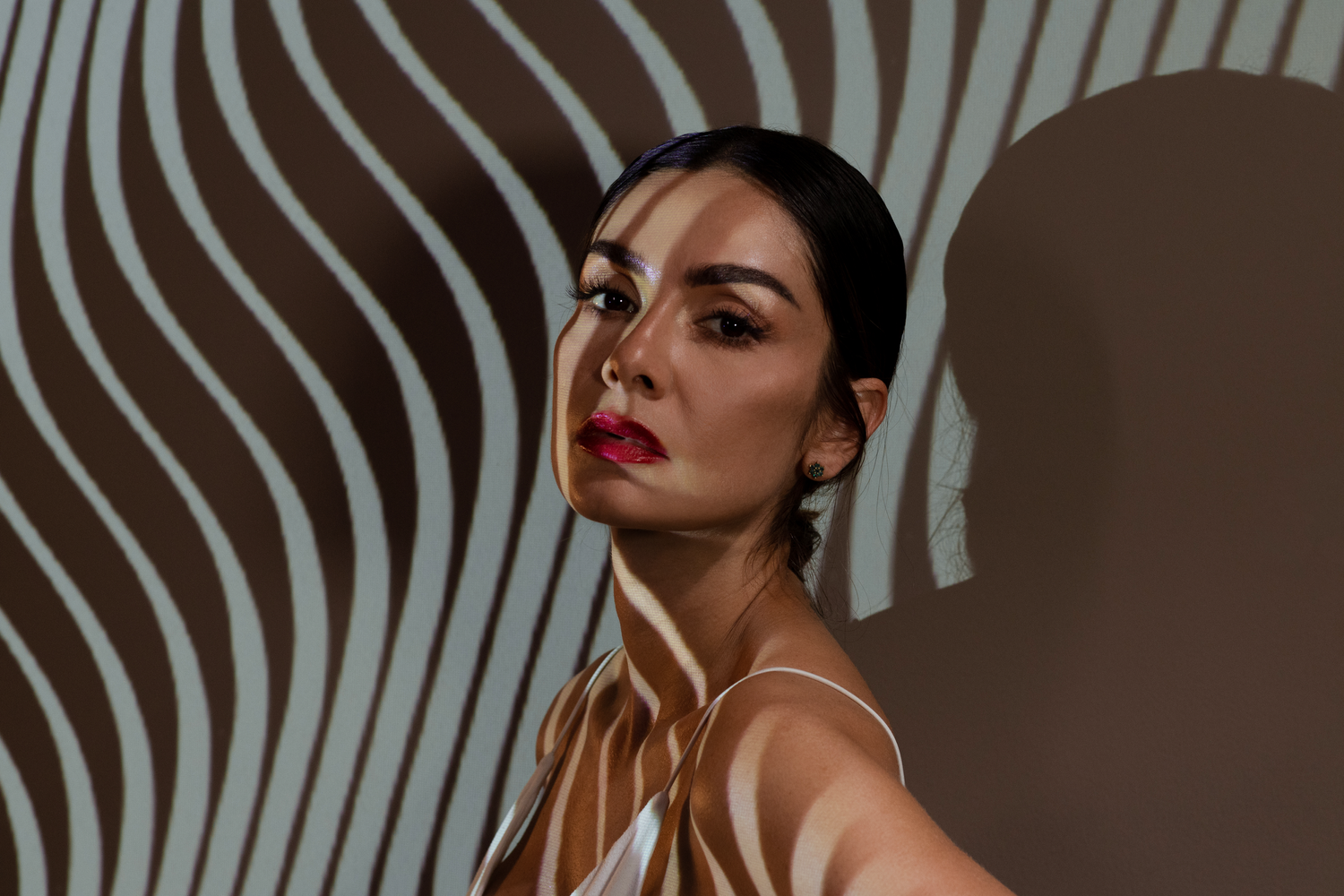 Artistic portrait with curved line shadows and dramatic lighting.