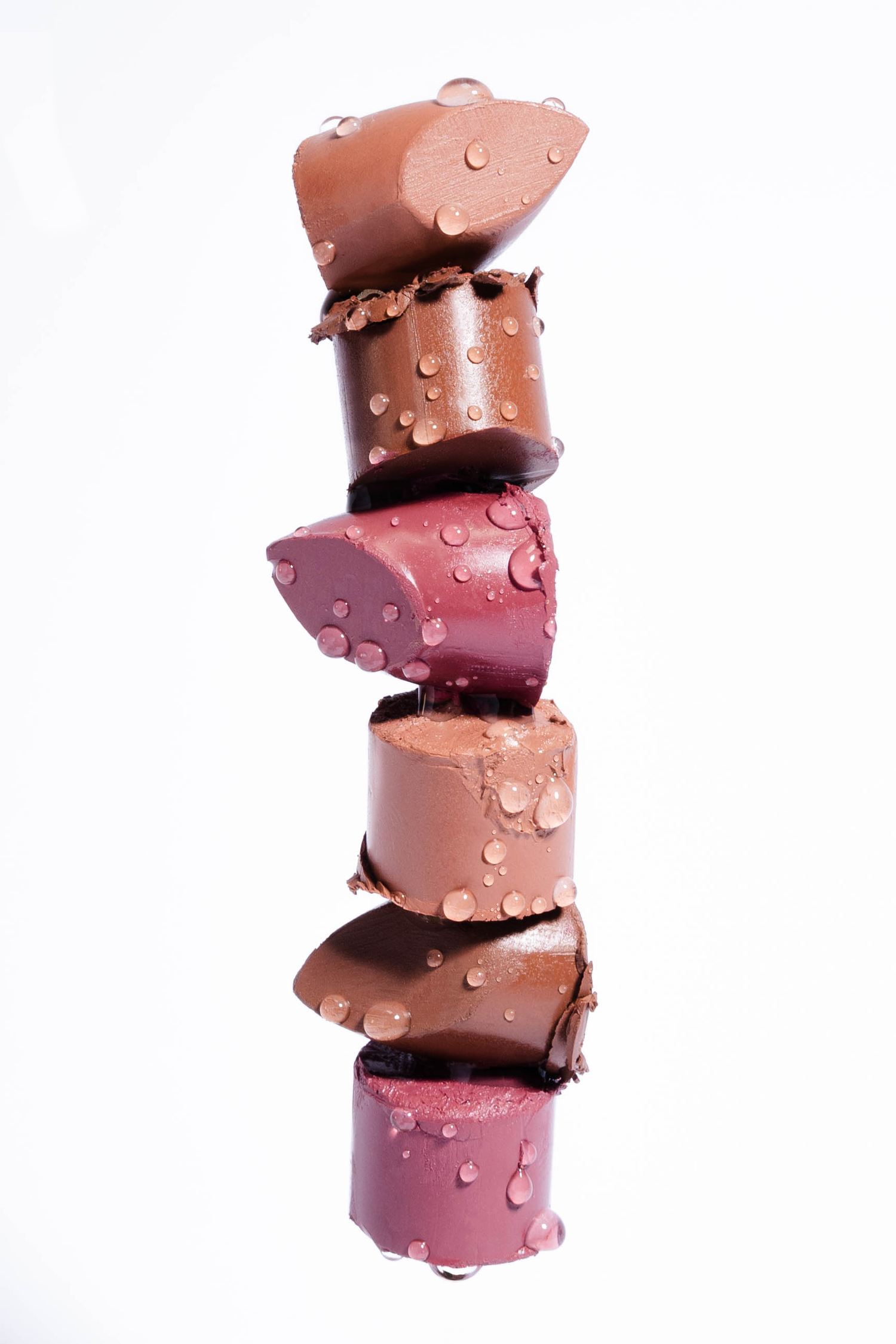 Artistic stack of chocolate pieces with water droplets against white background.