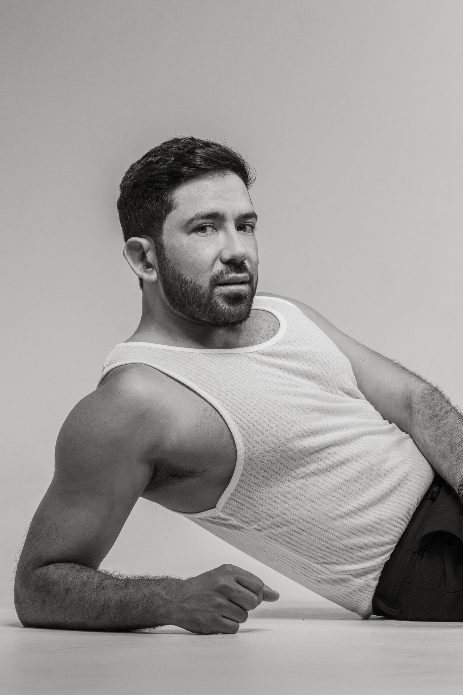 Athletic person in white tank top posing against neutral background.