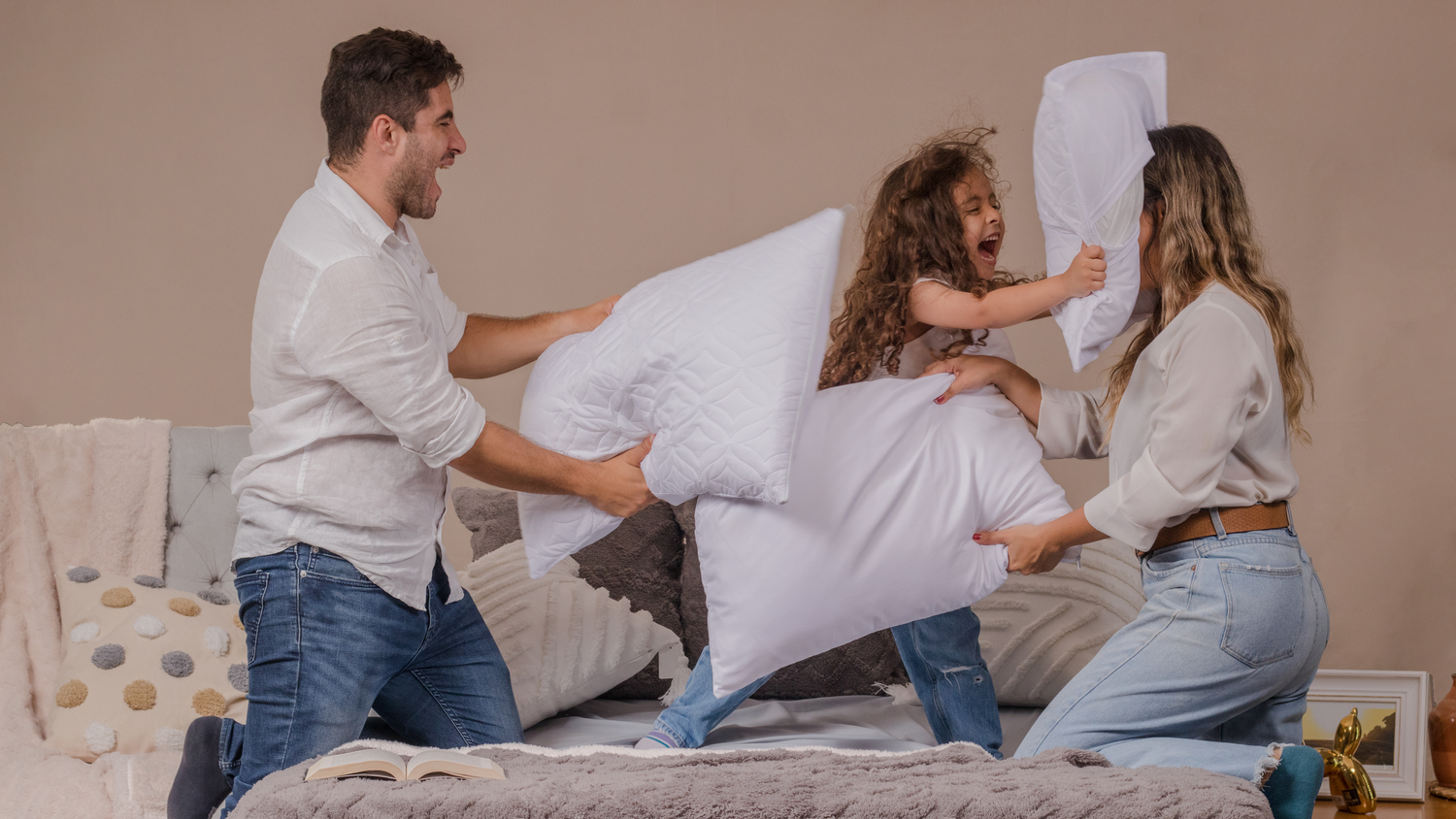 Playful pillow fight scene on a bed with three participants.
