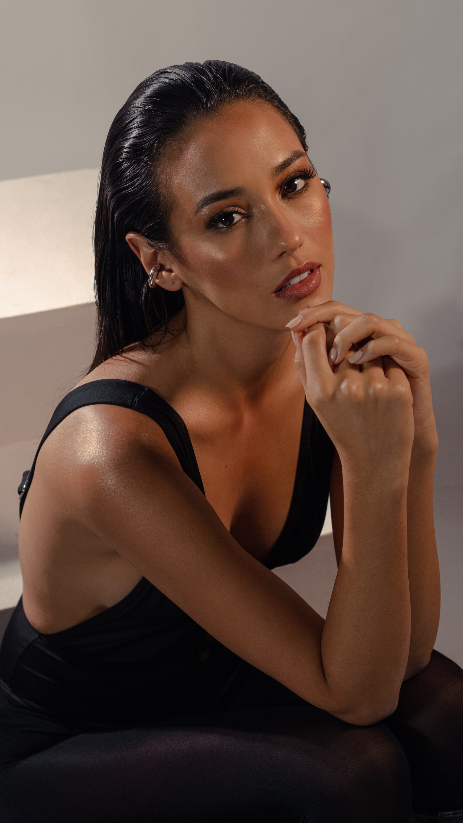 Beauty portrait with natural makeup and black top in warm studio lighting.