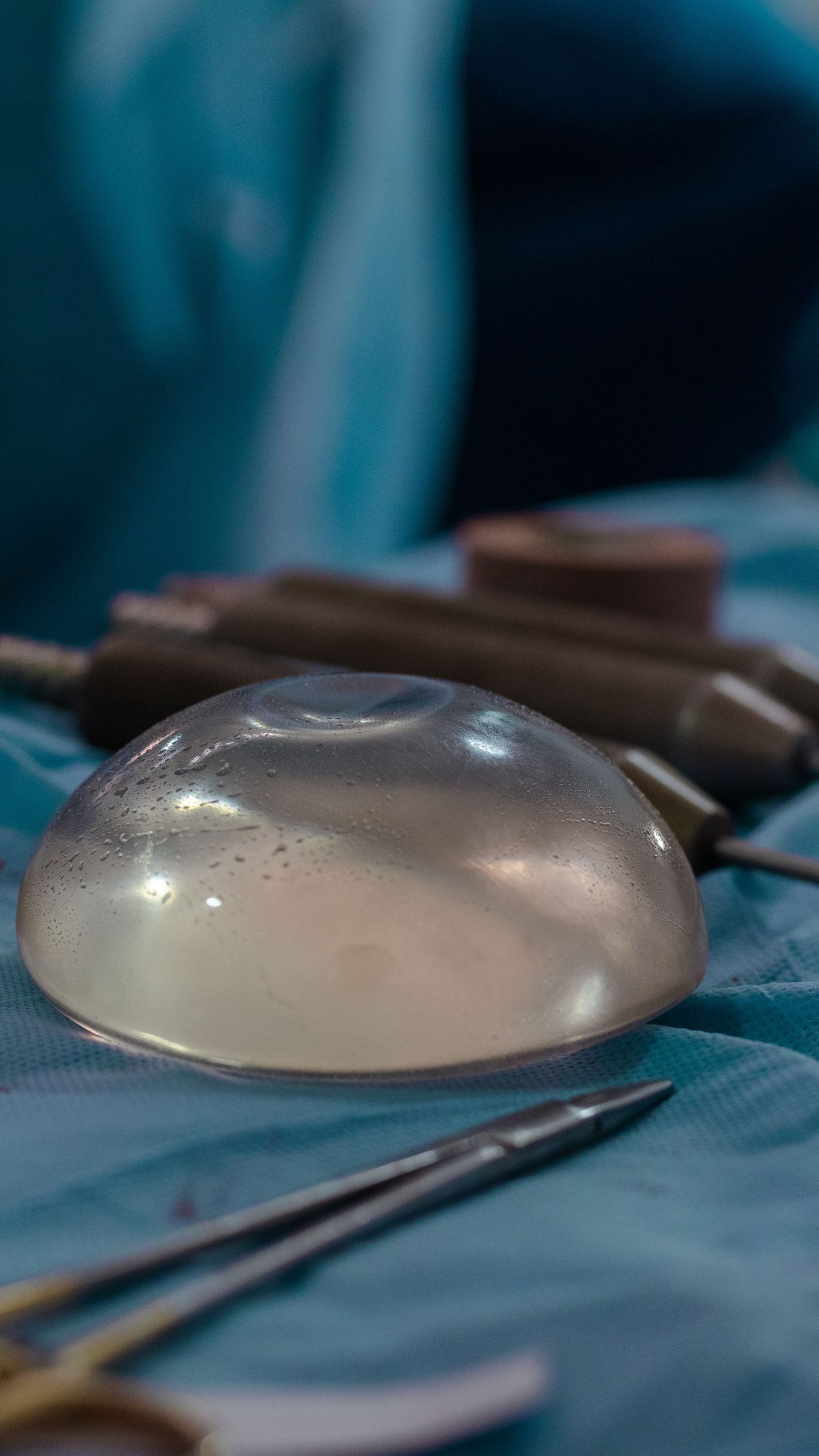Clear medical implant on surgical table with medical instruments in background.