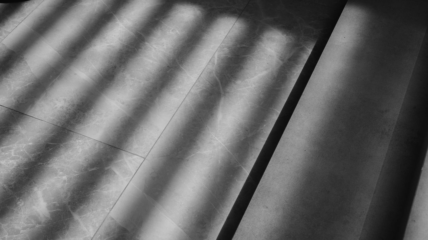 Abstract pattern of diagonal light and shadow lines on a white surface.