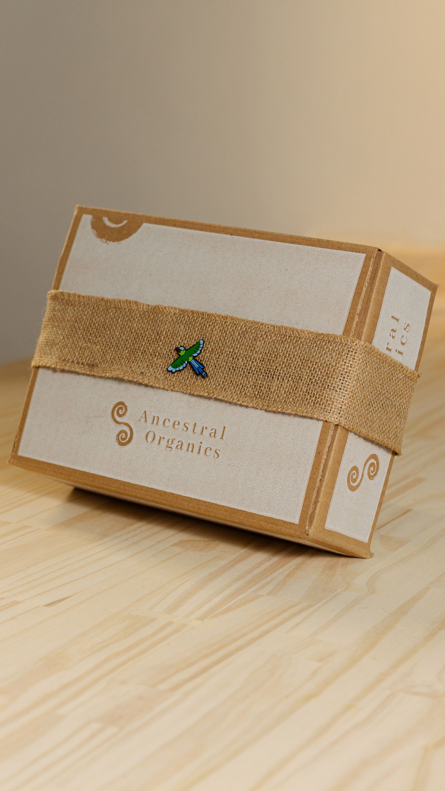 Eco-friendly gift box with burlap band and green leaf logo on wooden table.