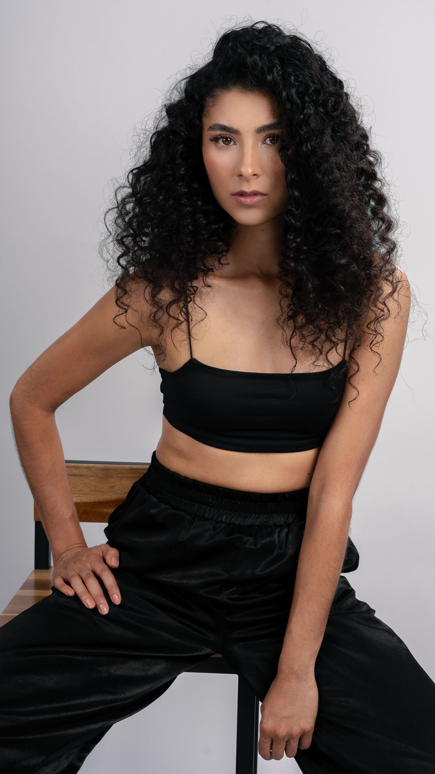 Contemporary fashion portrait in black crop top and pants with natural hair styling.