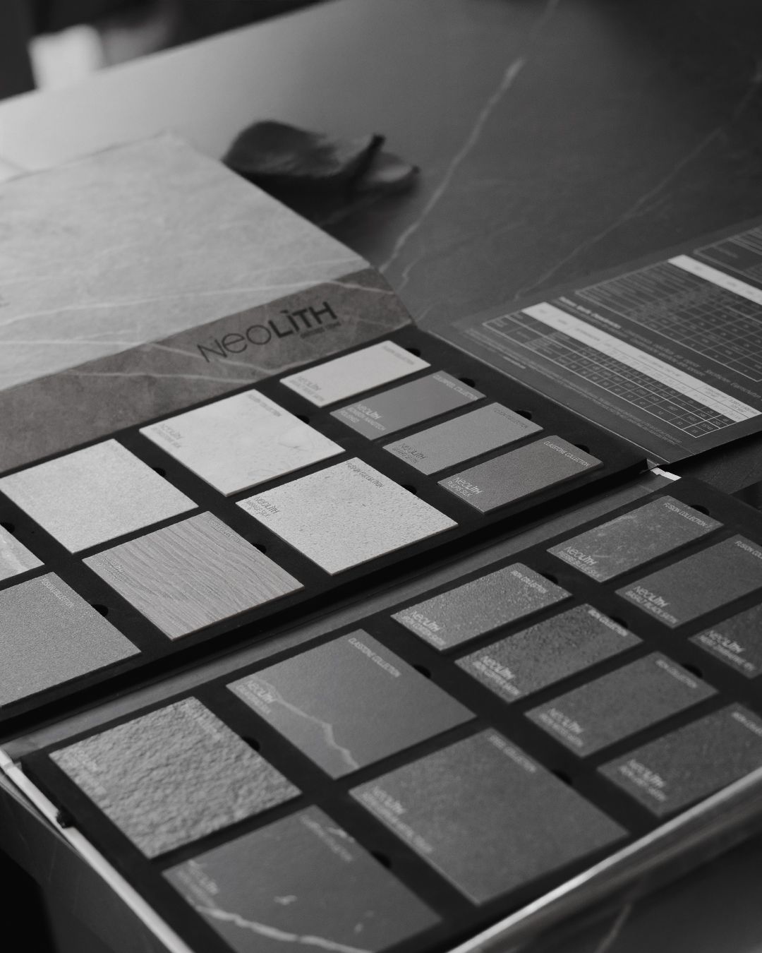 Black and white photograph of color swatches and design samples laid out on dark surface.