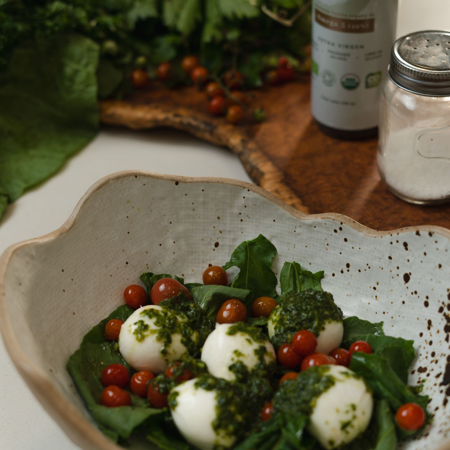 Fresh burrata salad with cherry tomatoes and greens on a decorative white plate.