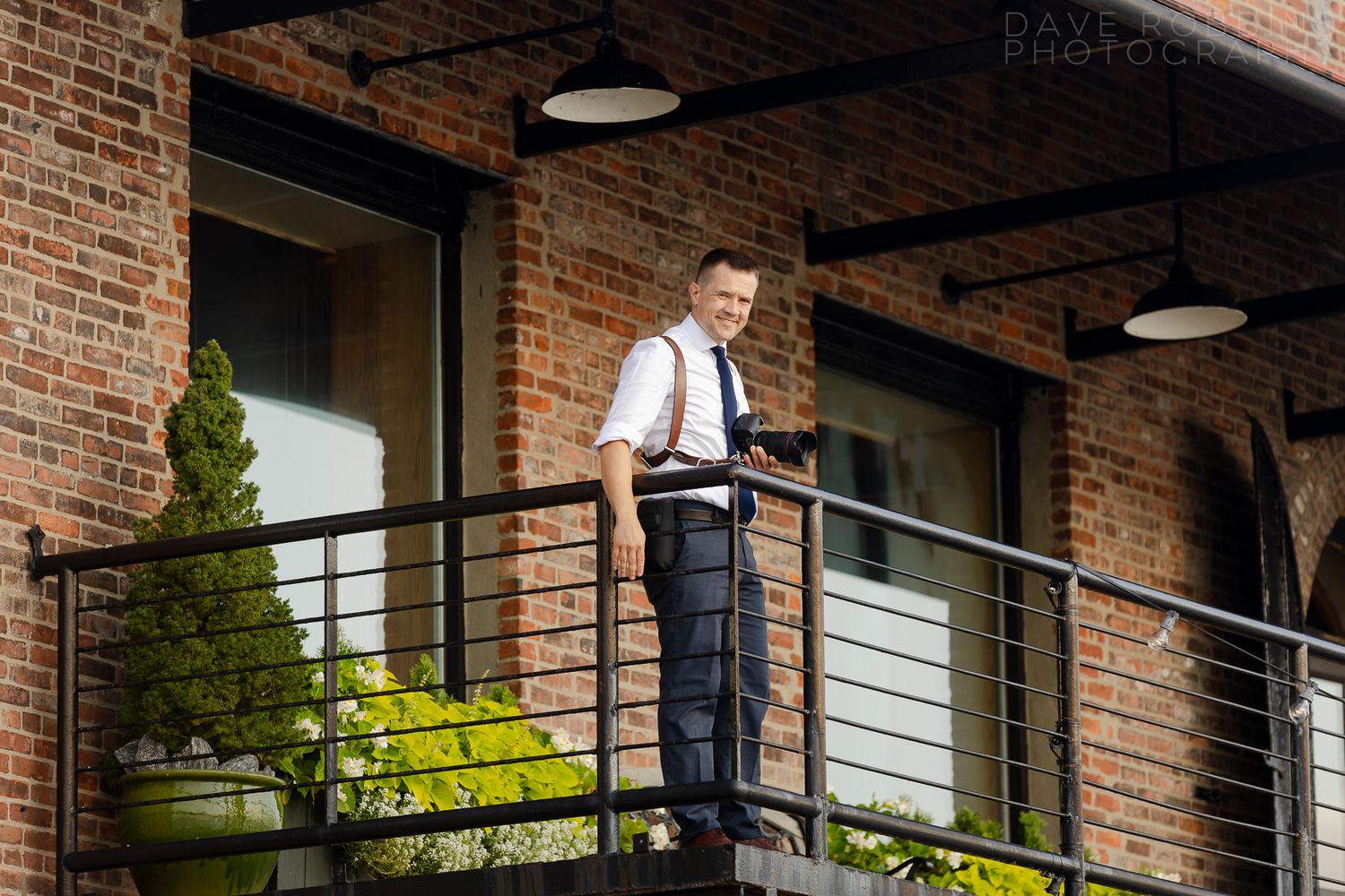 Modern industrial brick office building exterior with glass windows and balconies surrounded by greenery.
