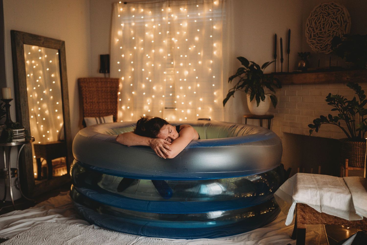 Birth setting with inflatable pool and twinkle lights creating cozy ambiance in dim room.