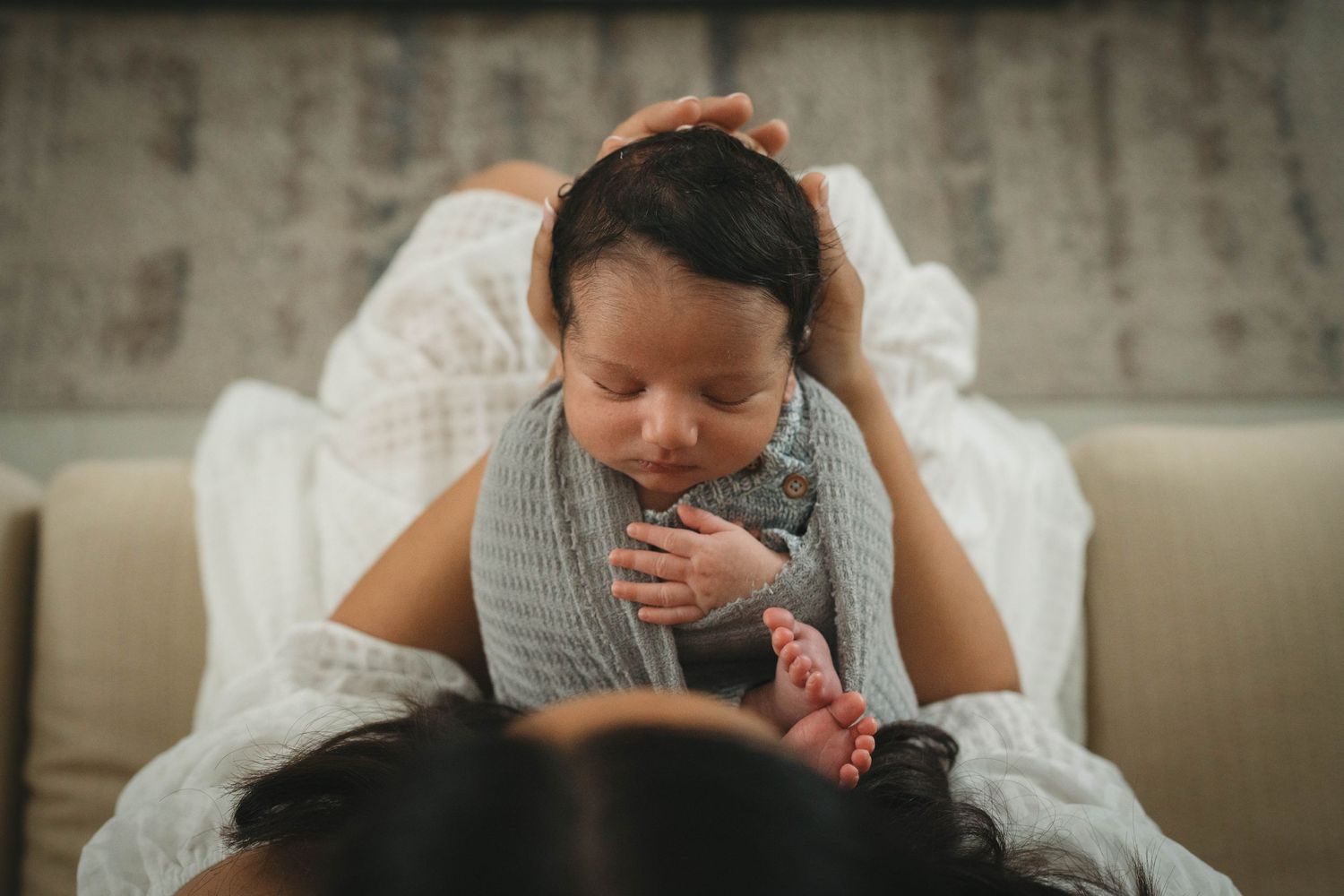 An intimate overhead view of a caregiver bonding with a baby on a couch.