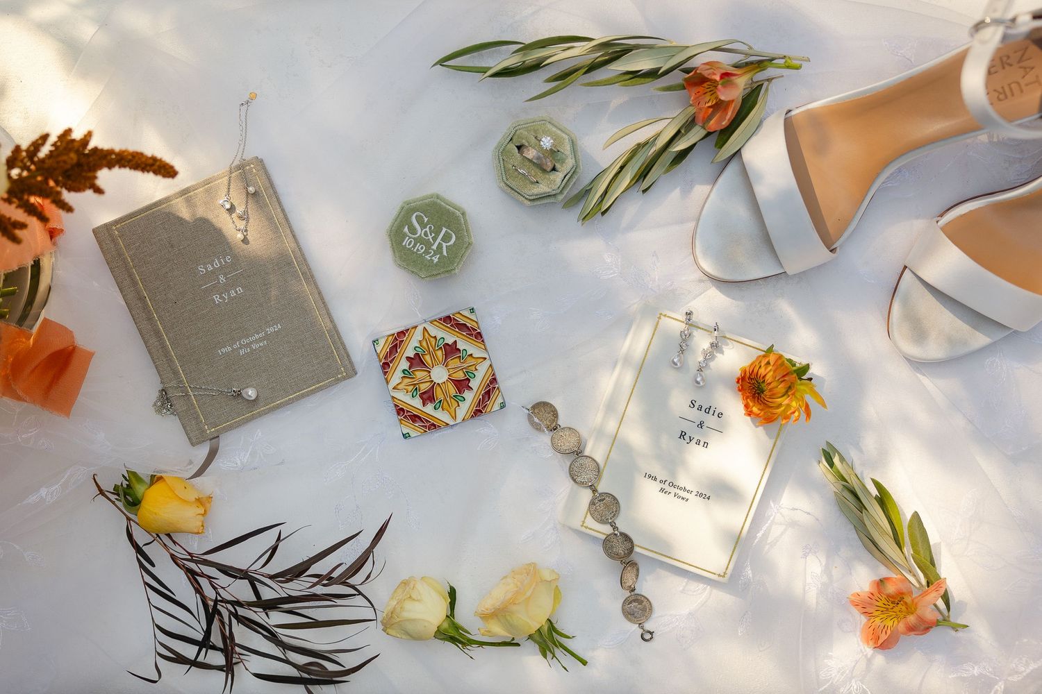 Wedding invitation suite with white and orange floral arrangements laid out on a light blue surface.