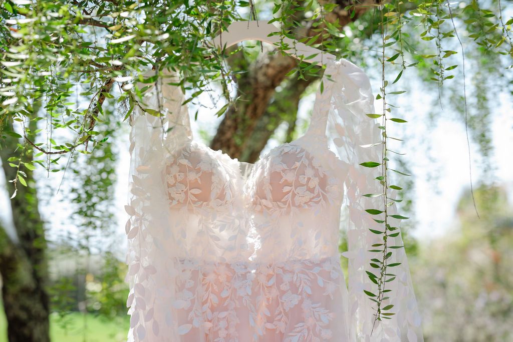 Delicate pink wisteria flowers cascade down in clusters against a soft blurred background in a garden setting.