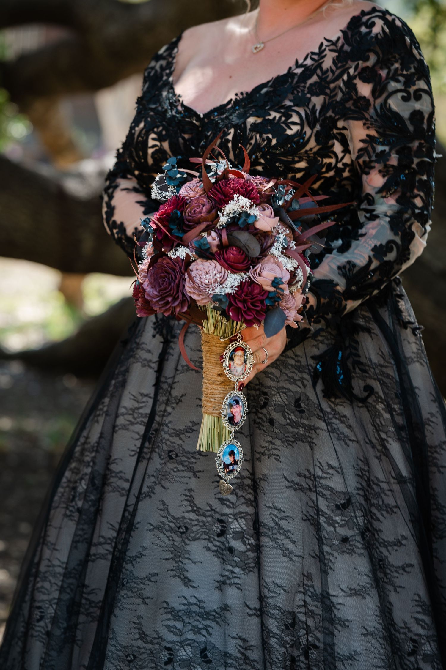 Close-up details of a black gothic wedding dress with lace overlay and deep burgundy floral bouquet accents.