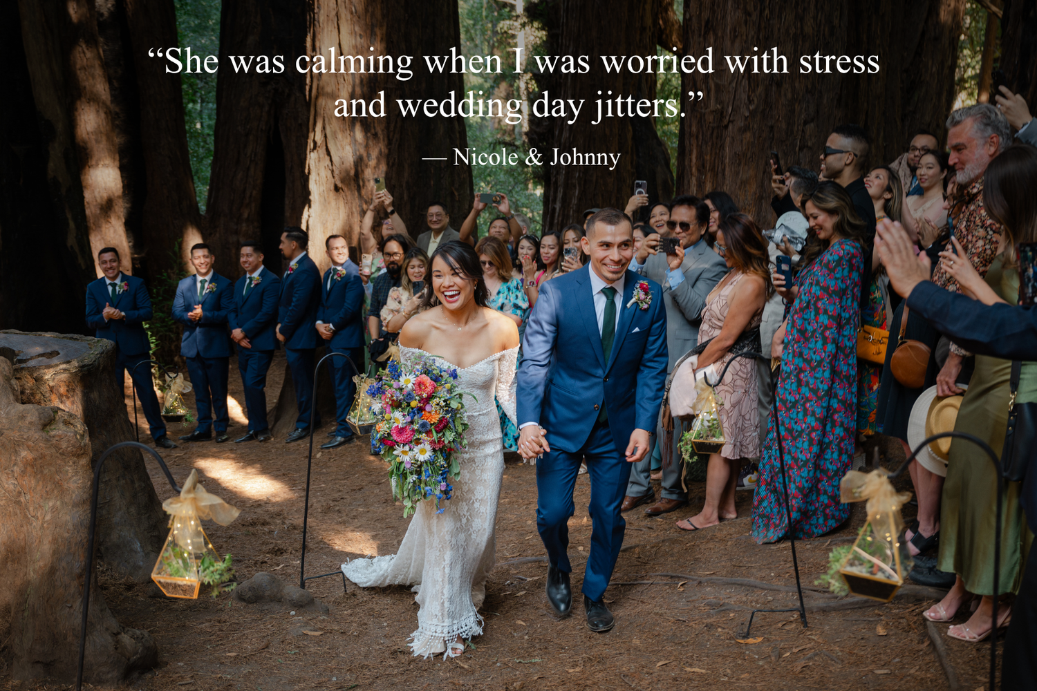 Happy newlyweds walk down the aisle in a redwood forest wedding ceremony surrounded by guests in blue attire.