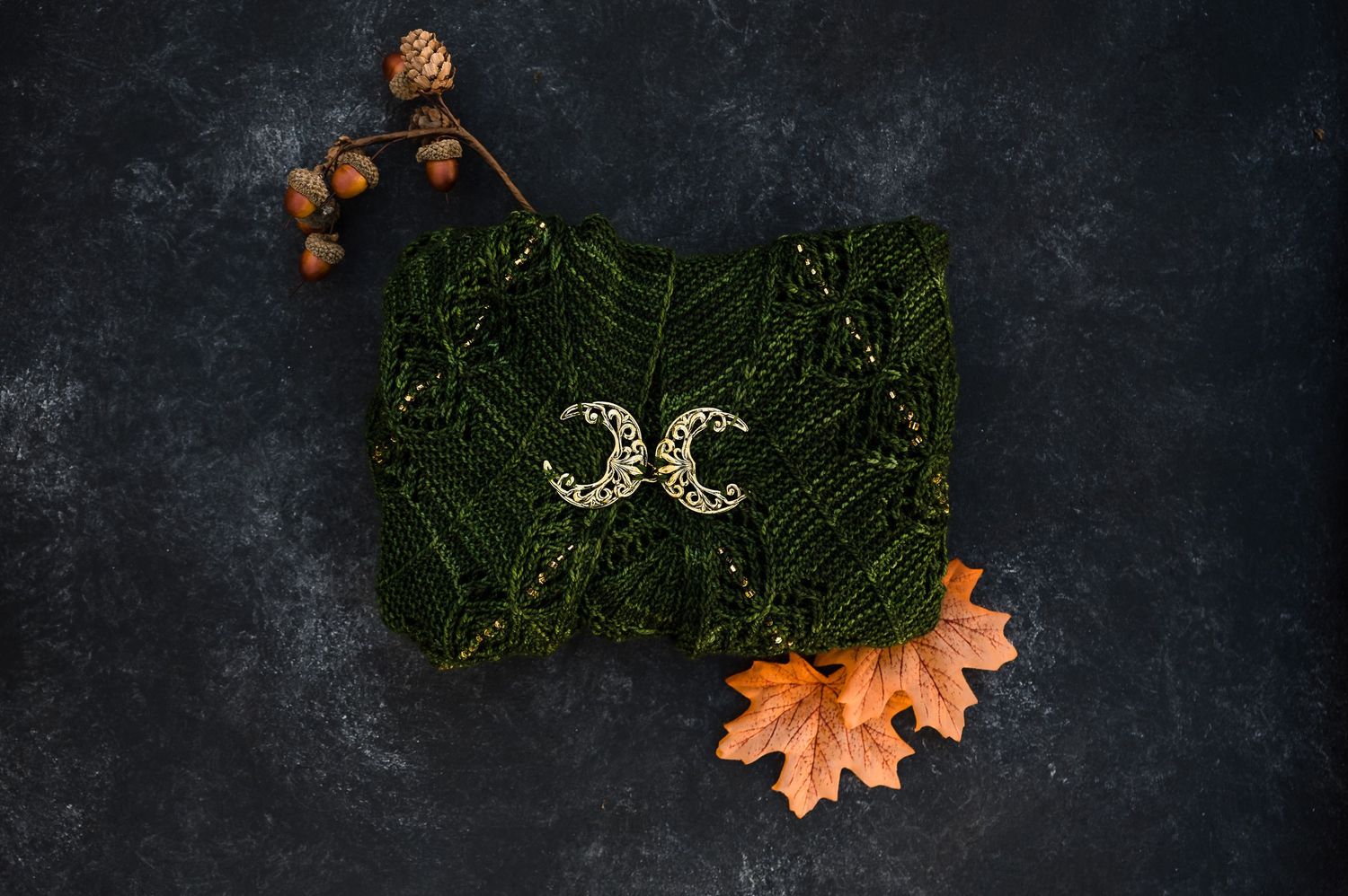Autumn themed food photography setup with dark background, scattered acorns, maple leaves, and evergreen branches.