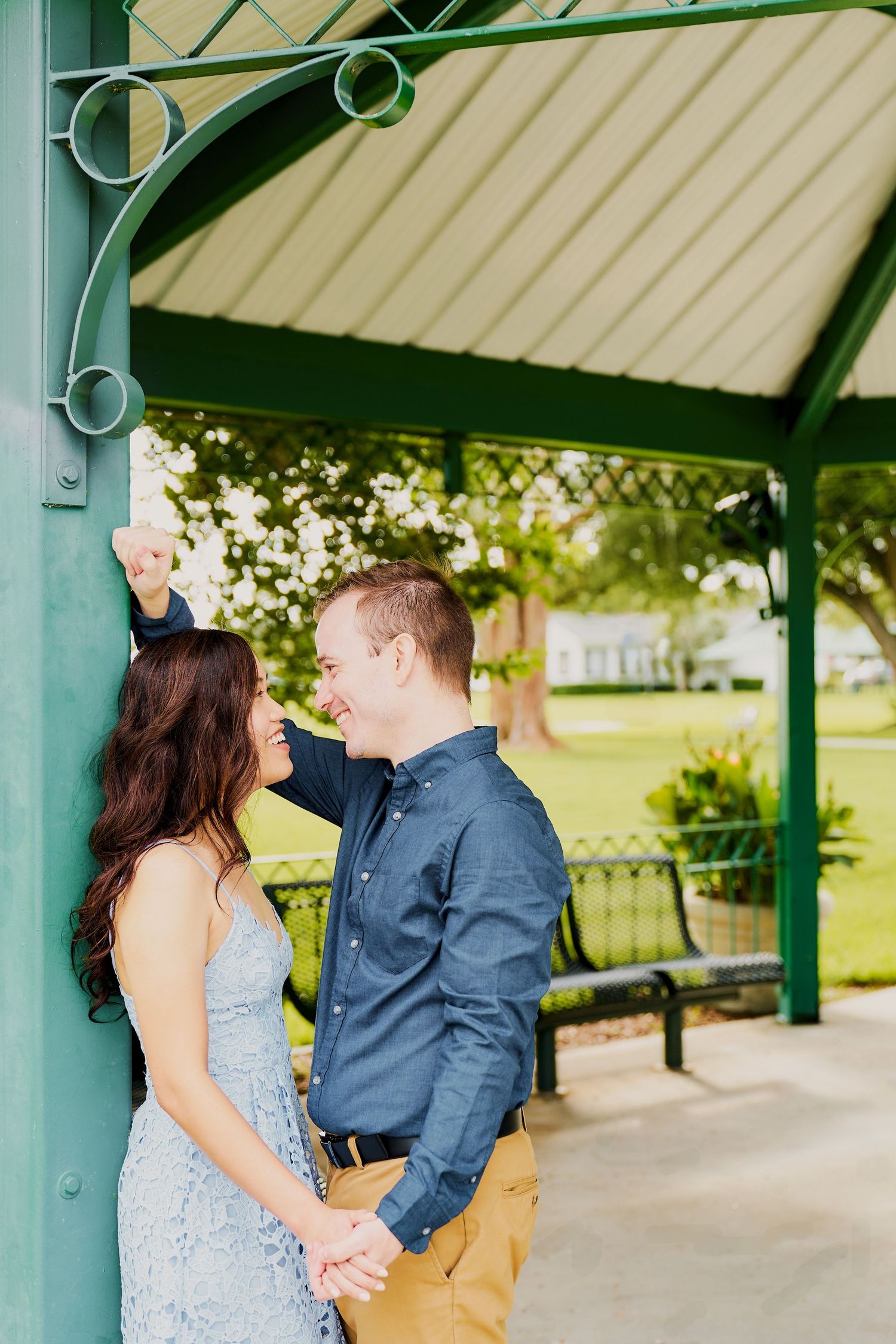 A romantic moment captured under a green gazebo in a park setting with soft lighting and natural decor.
