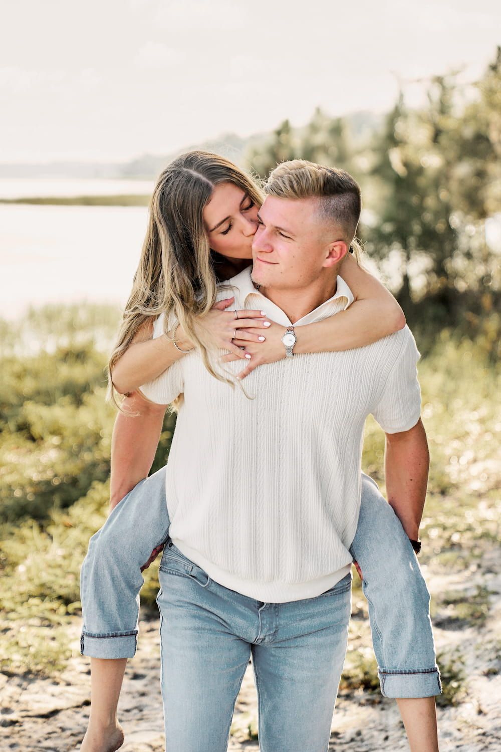 A couple in casual denim and white clothing share intimate moments during a romantic outdoor photoshoot.