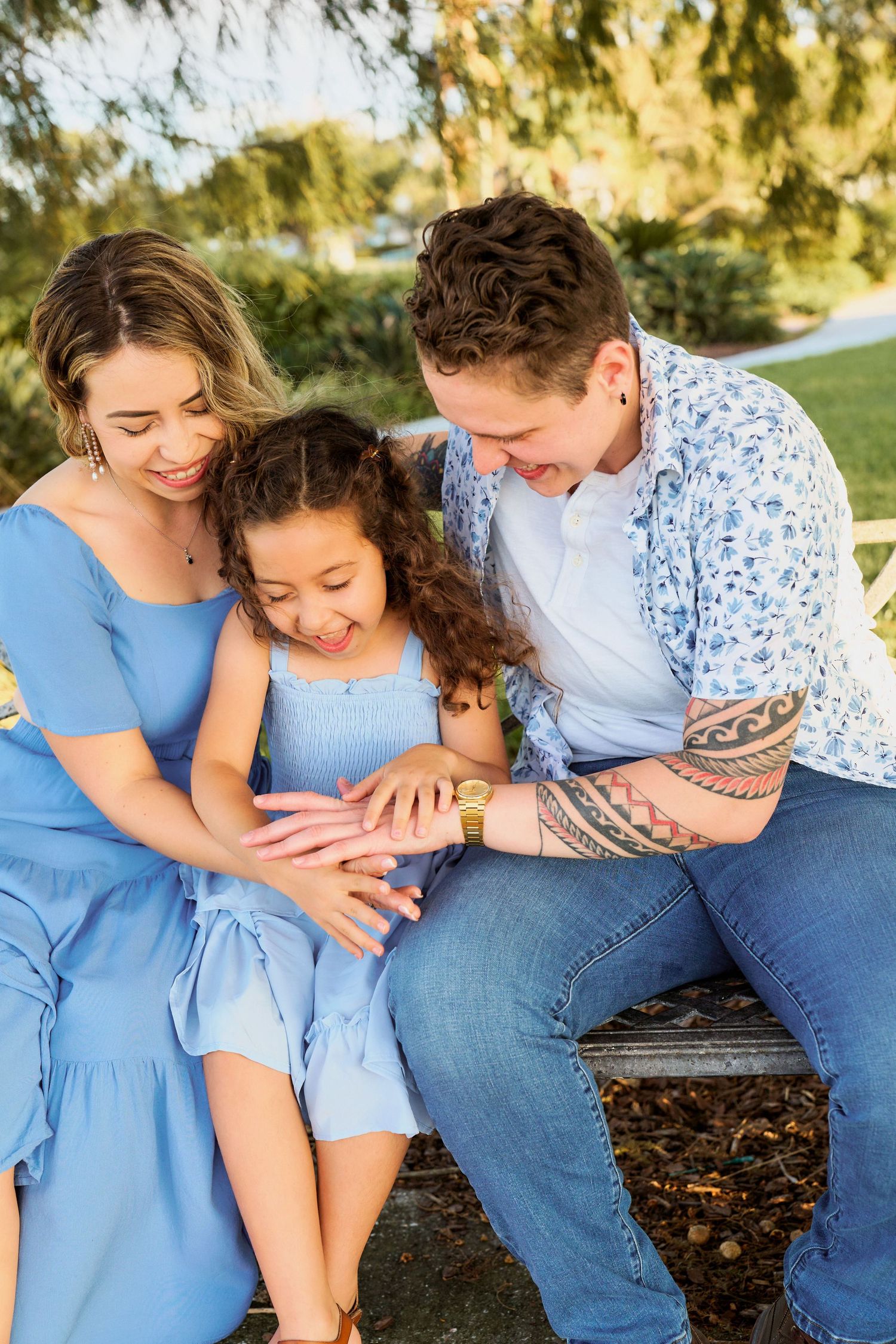 A couple in coordinating blue outfits share loving moments together outdoors during a sunset photoshoot.