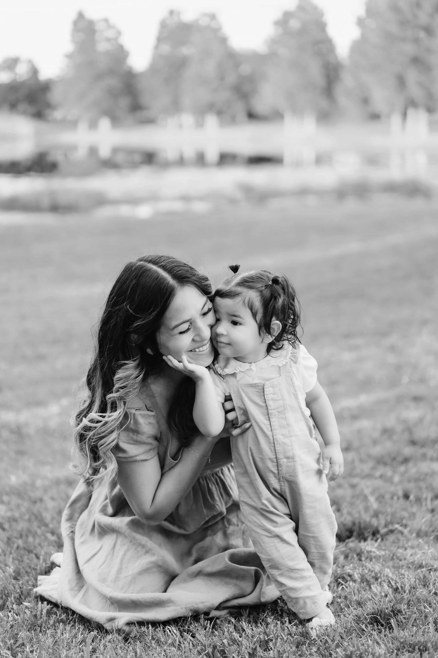 A tender black and white photo series of a mother and child sharing loving moments together on the grass.