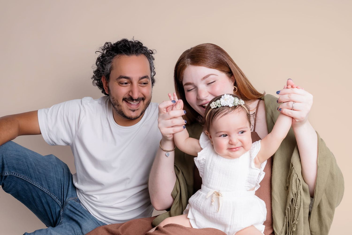 A series of tender moments between parents and their baby wearing a white dress and headband.