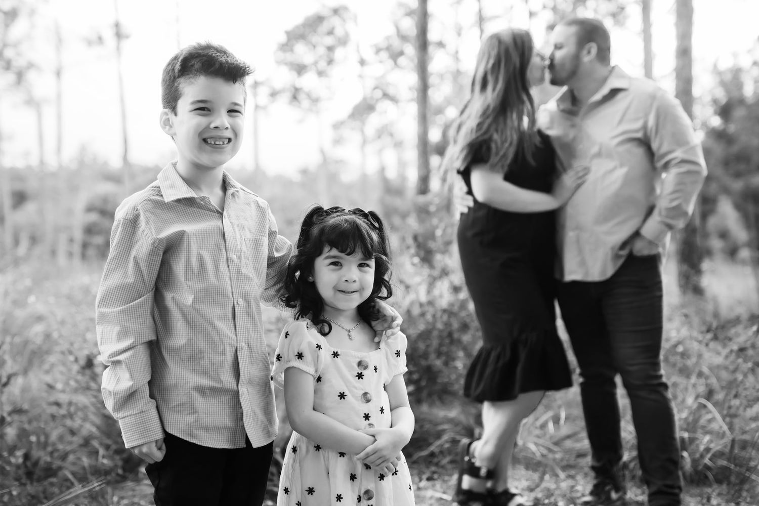 Black and white photo collage of a family enjoying candid moments together outdoors in a natural setting.