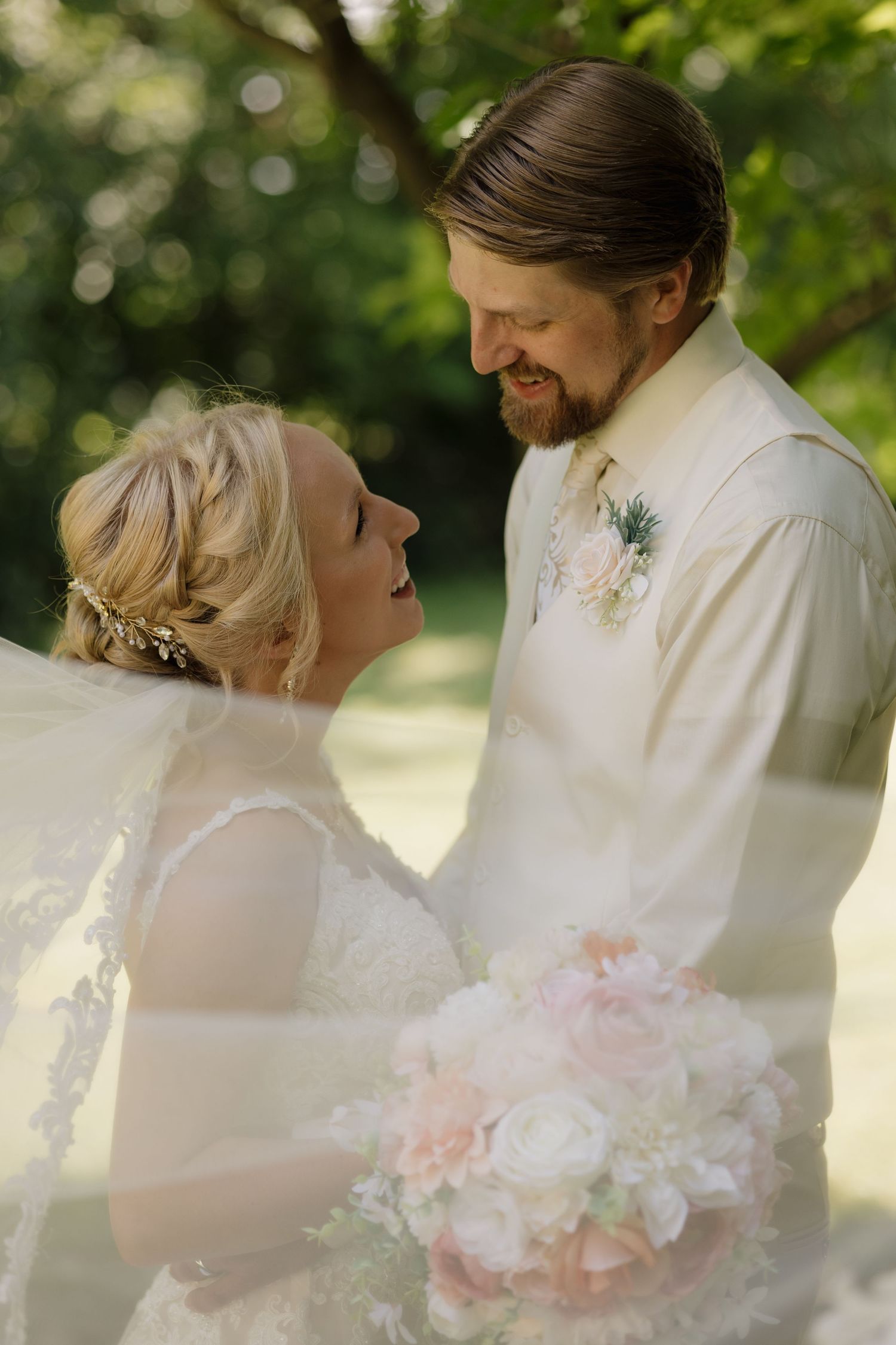 A joyful wedding moment captured outdoors with a beautiful bouquet of pink and white flowers in natural lighting.