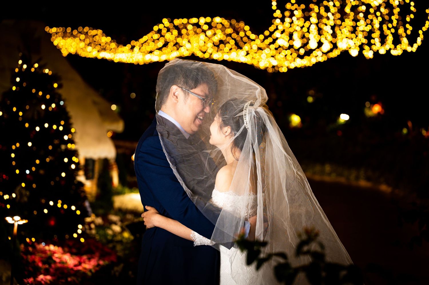 A romantic wedding couple shares their first dance under twinkling string lights at an evening reception.