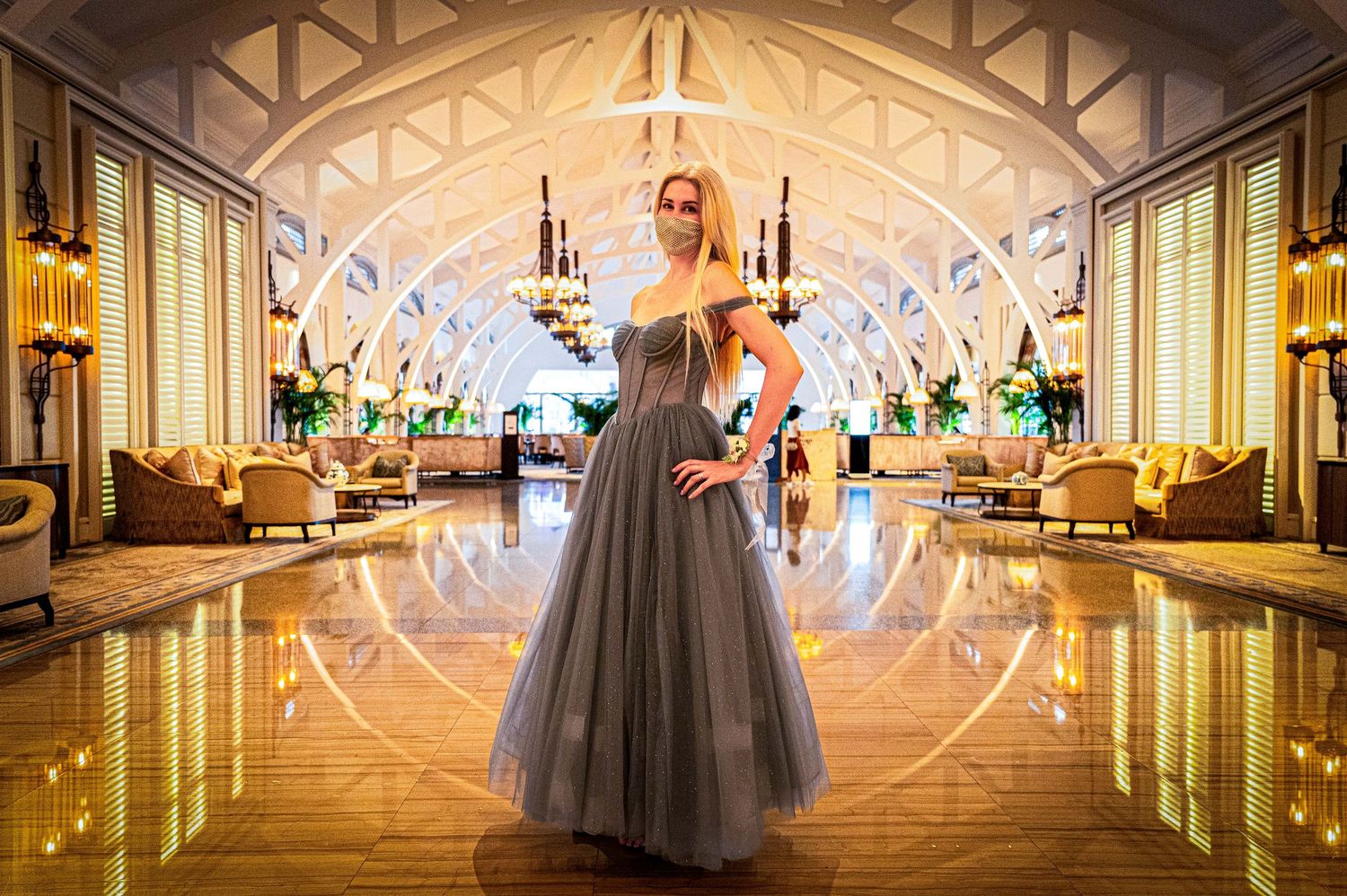 A long mirrored hallway with elegant chandeliers and ornate decor reflecting luxurious wedding reception details.