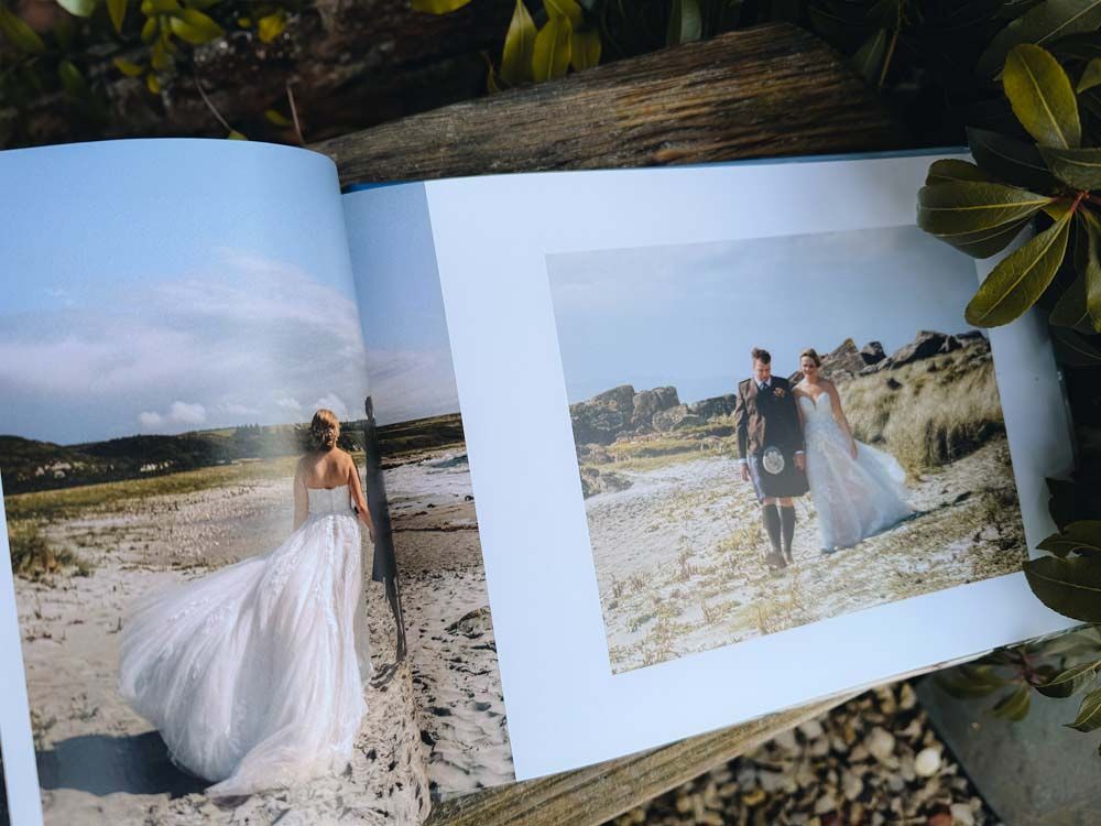 A photo album displays romantic beach wedding photography with flowy white dress and coastal scenery in the background.