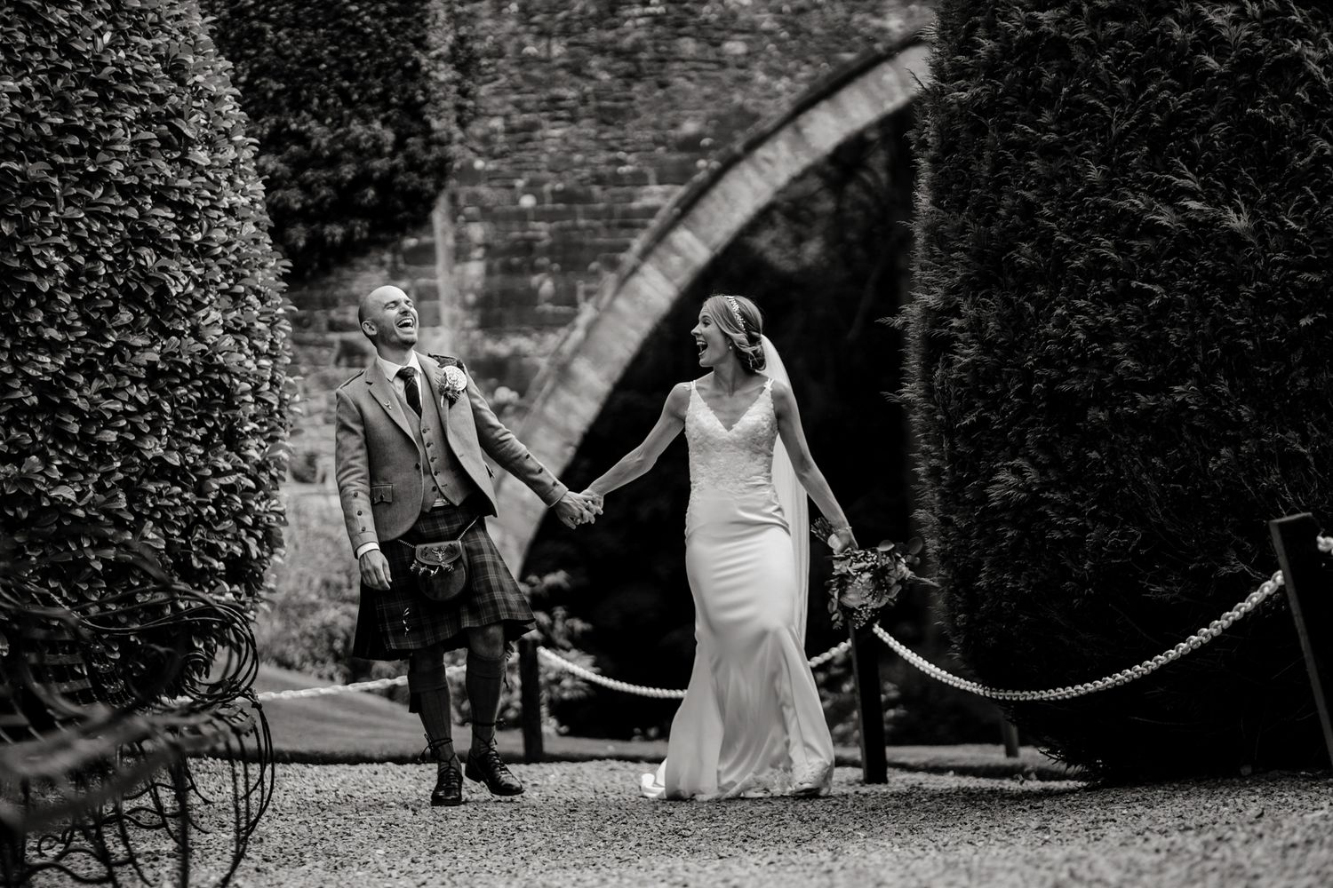 Black and white wedding photo sequence showing couple walking and dancing together in an outdoor garden setting.
