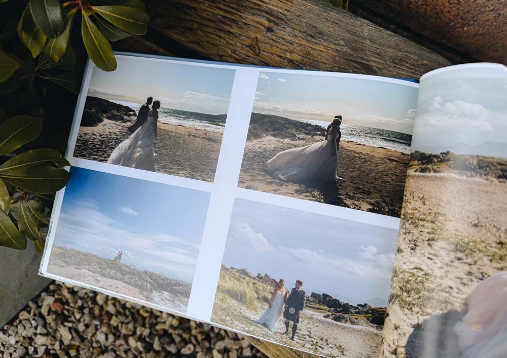 Photo album pages showing scenic coastal landscapes with sandy beaches and ocean views laid on wooden surface.
