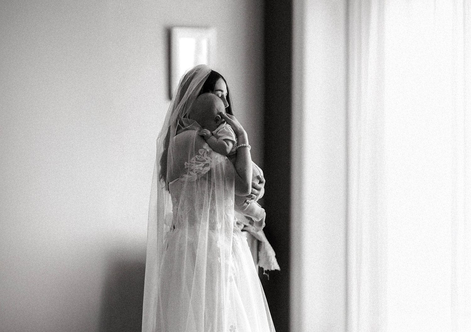 A series of black and white wedding photos showing a bride in a flowing veil near a window.