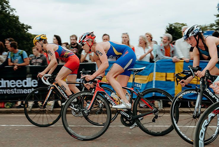 Professional cyclists lean into a tight turn during a high-speed road race competition on a city street.