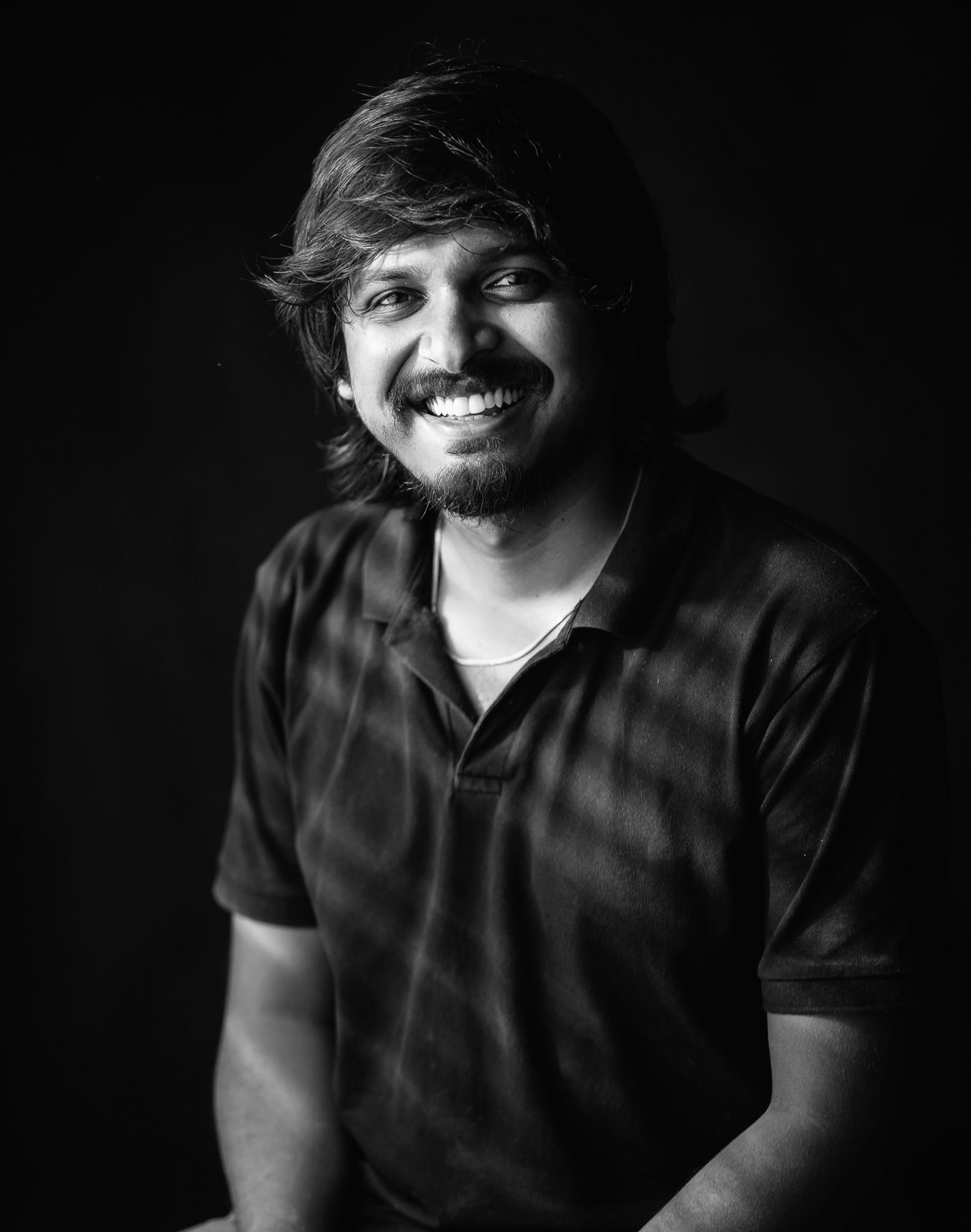 Black and white portrait showing a warm smile against dark background of Jeno Johnson, founder of Jeno Photography