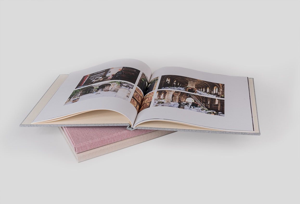 Livre photo ouvert posé sur un autre album à couverture rose, pages intérieures visibles