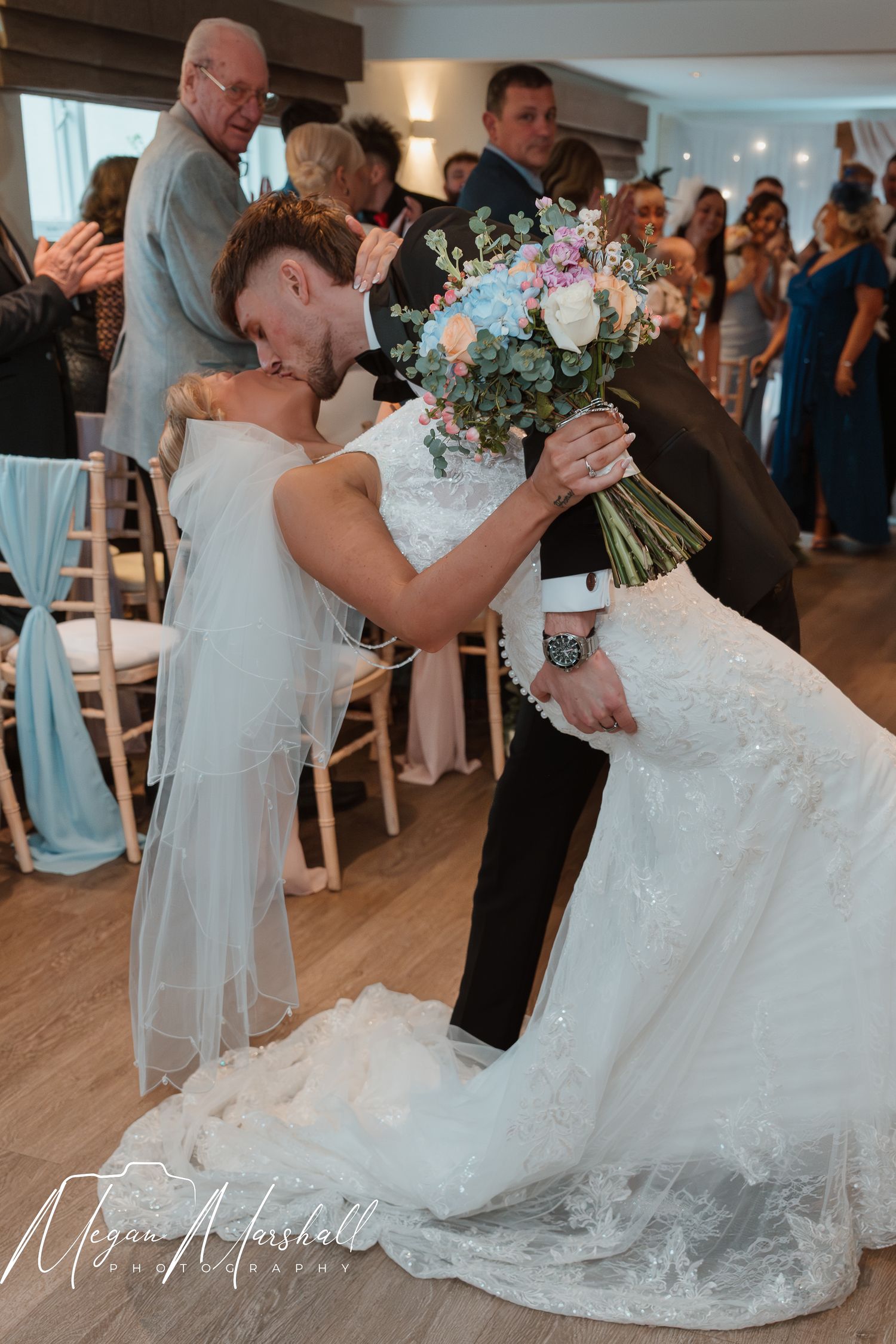 Bride and groom share a romantic dip kiss on the dance floor during their wedding reception.