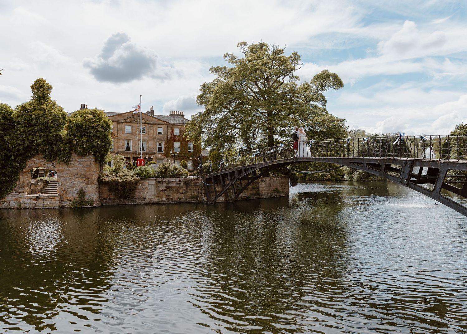 Panoramic view of Amsterdam canals with historic buildings and bridges reflecting in calm waters under cloudy skies.