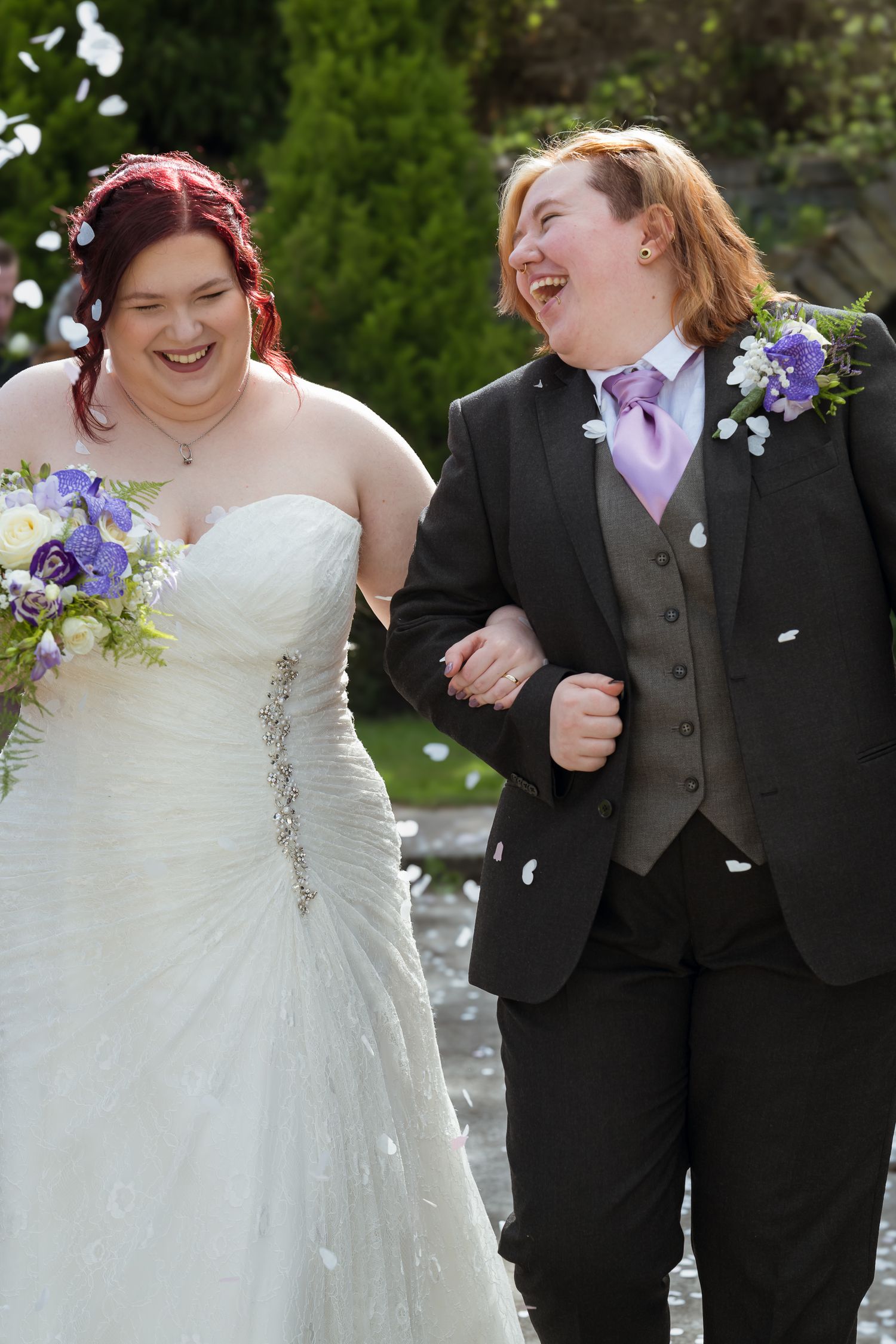 The New Inn Penistone. A joyful wedding couple shares a candid moment together as white flower petals fall around them outdoors.
