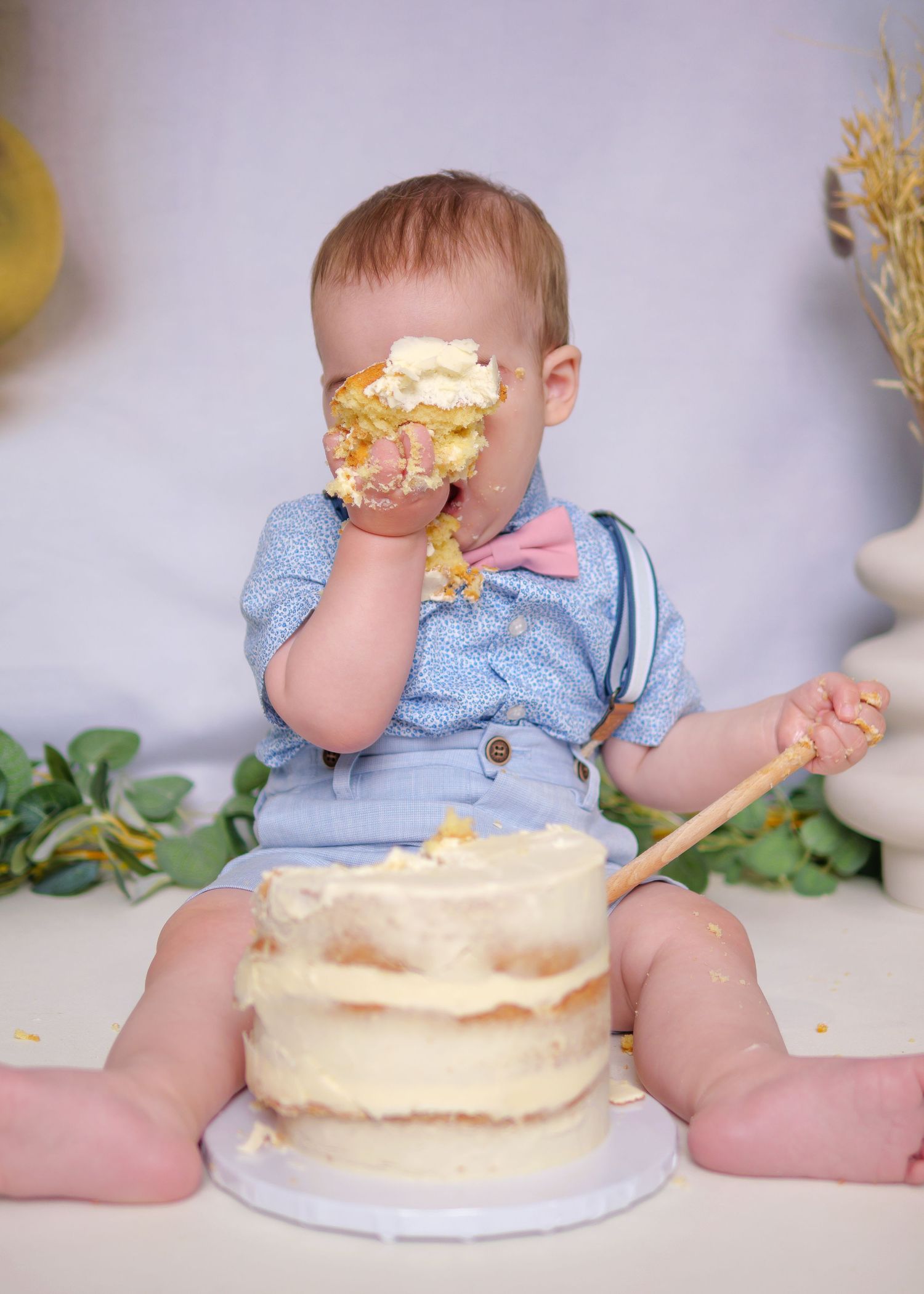 Baby's cake smash photo session with cream frosted cake and blue outfit. Cake Smash Photoshoot