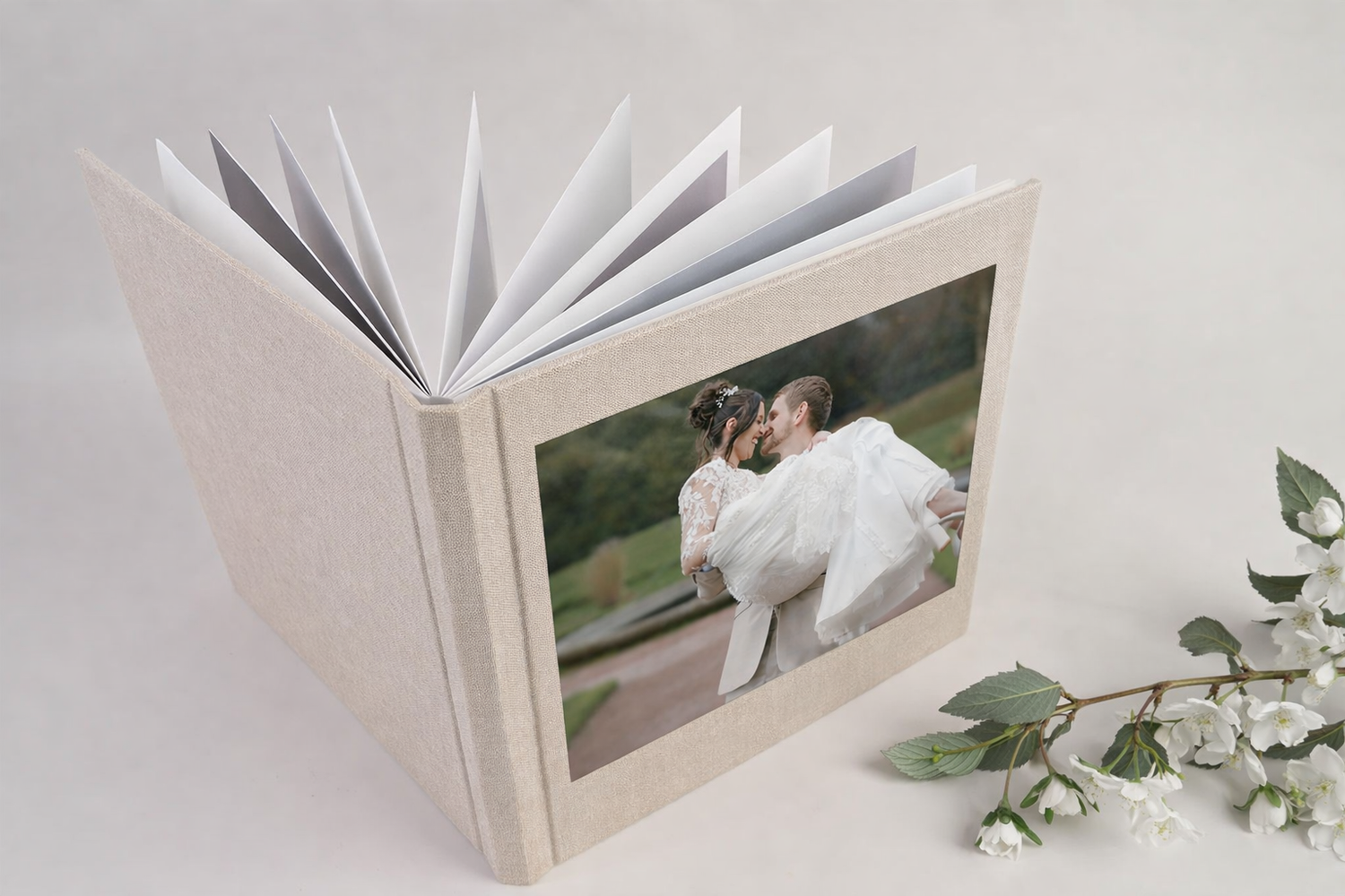 Open wedding photo album with couple kissing on cover. Front page shows Wortley Hall with married couple.