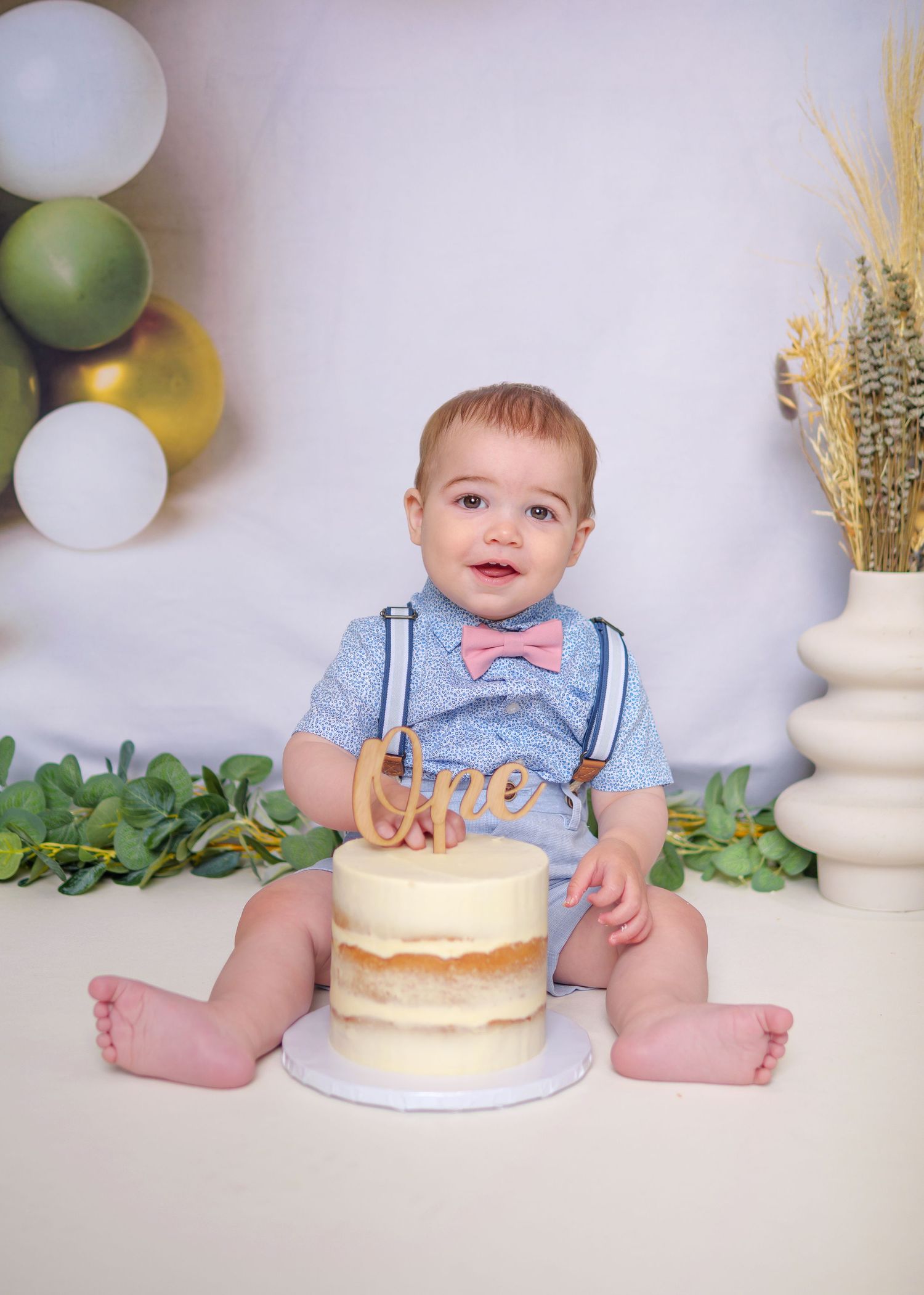 A series of cake smash photos showing a baby in blue celebrating with a white birthday cake. Cake Smash Photoshoot