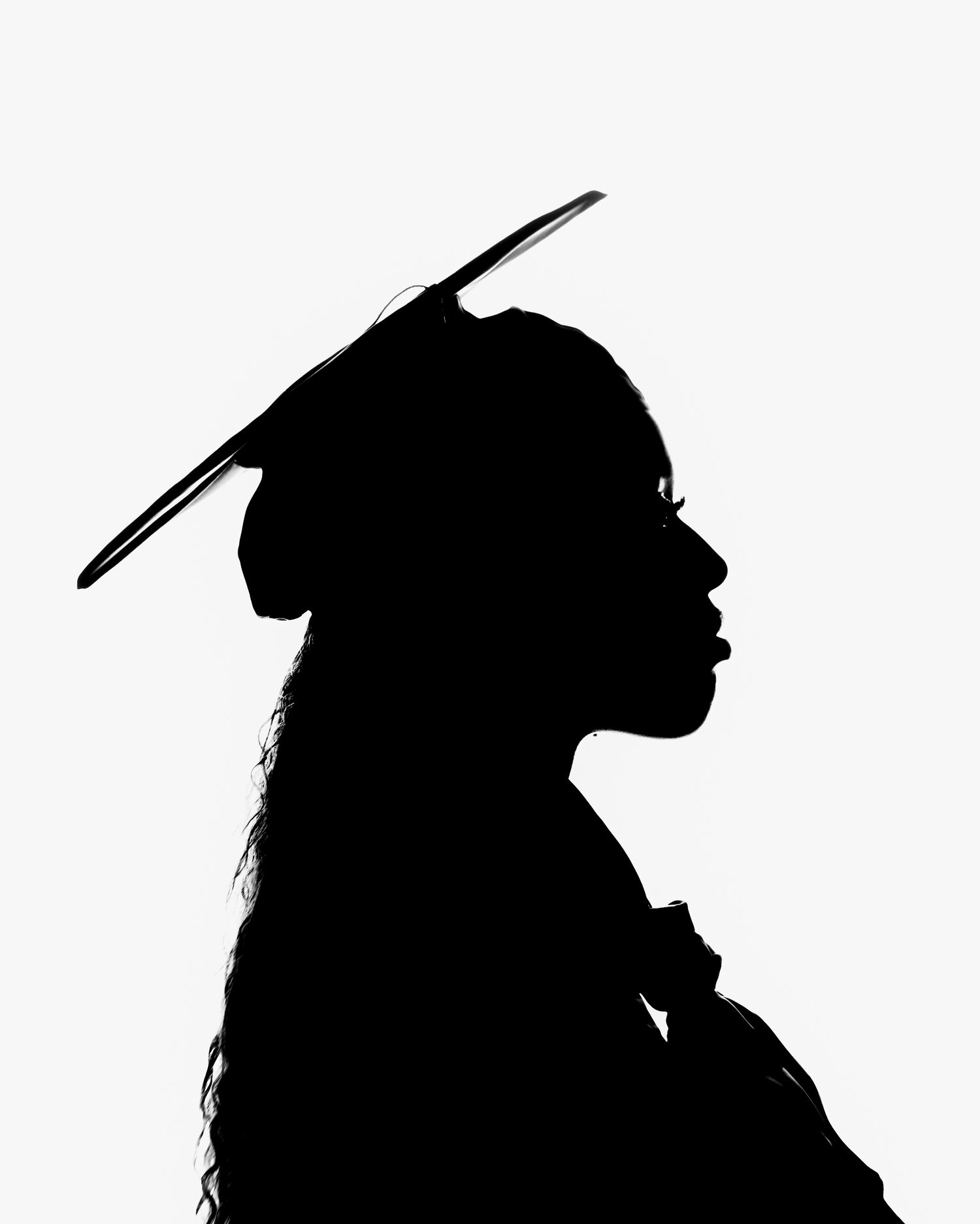 Silhouette profile of a graduate wearing a mortarboard cap against a white background.