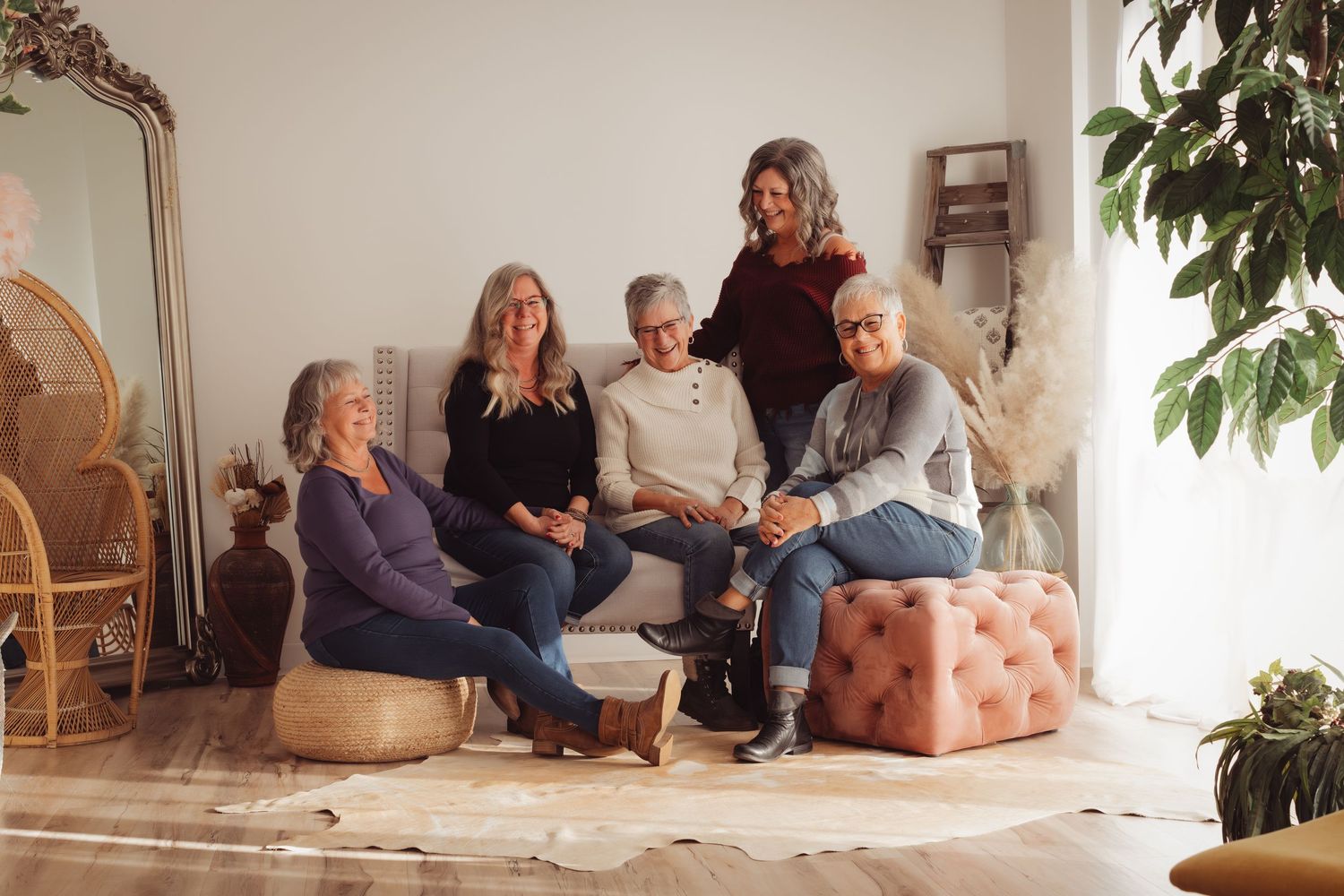 Group gathered in a cozy living room setting with decorative mirror, plants and comfortable seating arrangements.