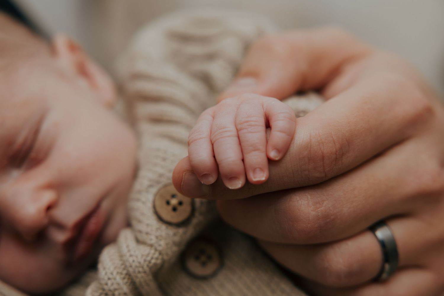 Close up detail view of tiny baby feet and gentle hands in soft neutral tones and textures.