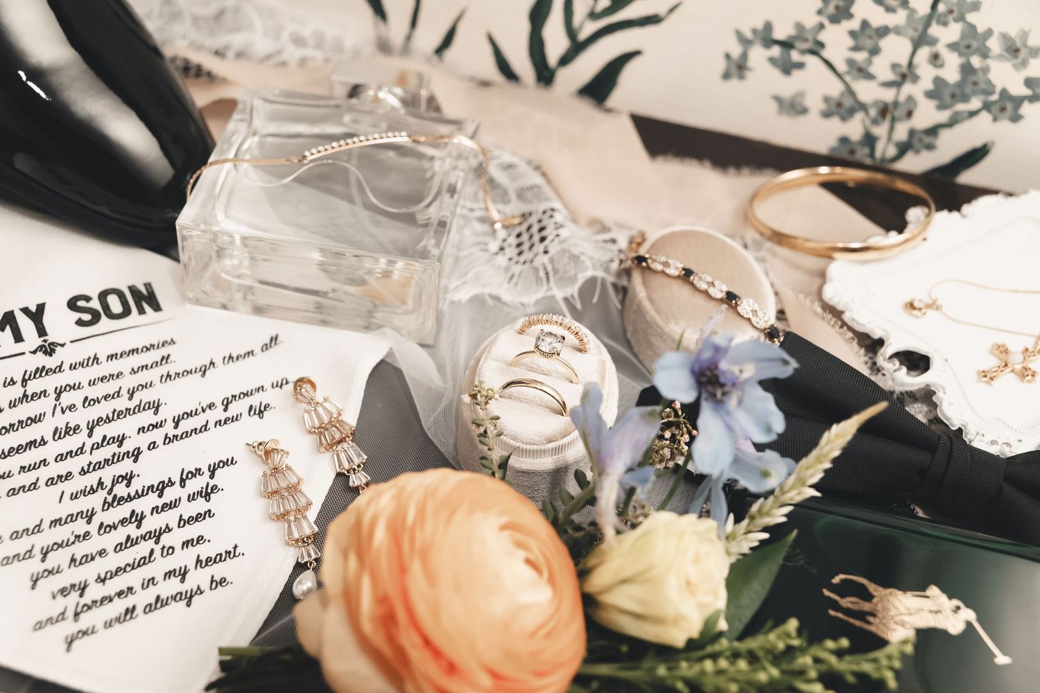 Elegant wedding flatlay featuring jewelry, florals, and a heartfelt letter—soft, sentimental moments that set the tone for a beautiful day.