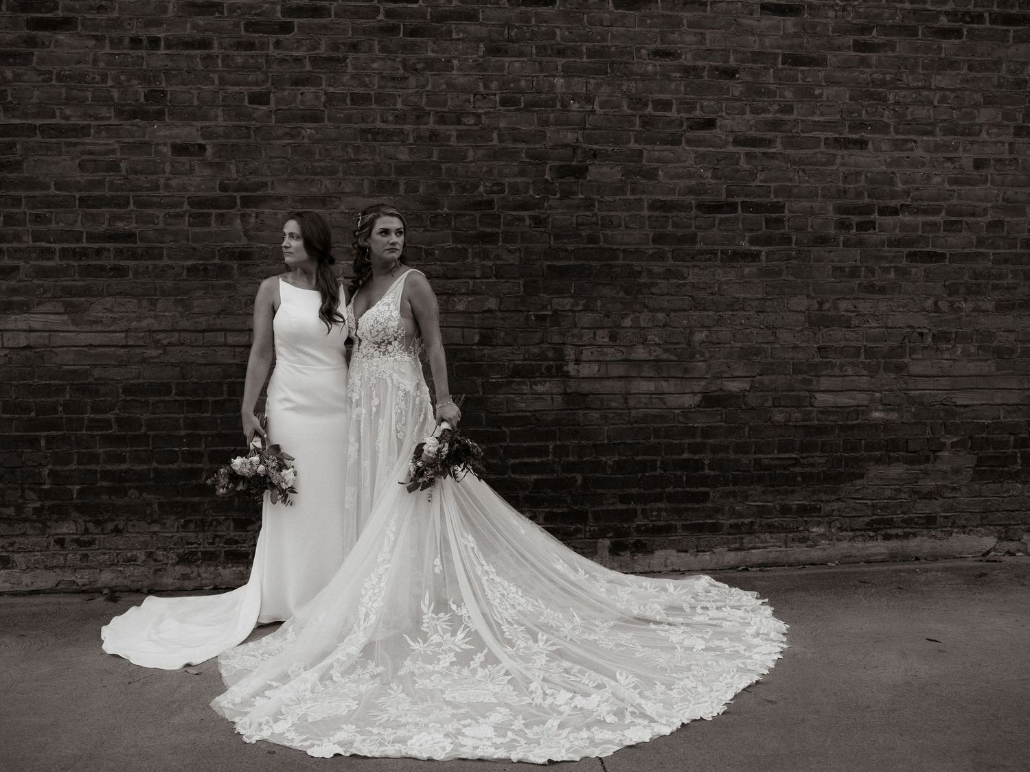 Editorial LGBTQ+ wedding in Cleveland, Ohio. Two brides in modern gowns, urban brick backdrop, timeless, romantic, inclusive photography.