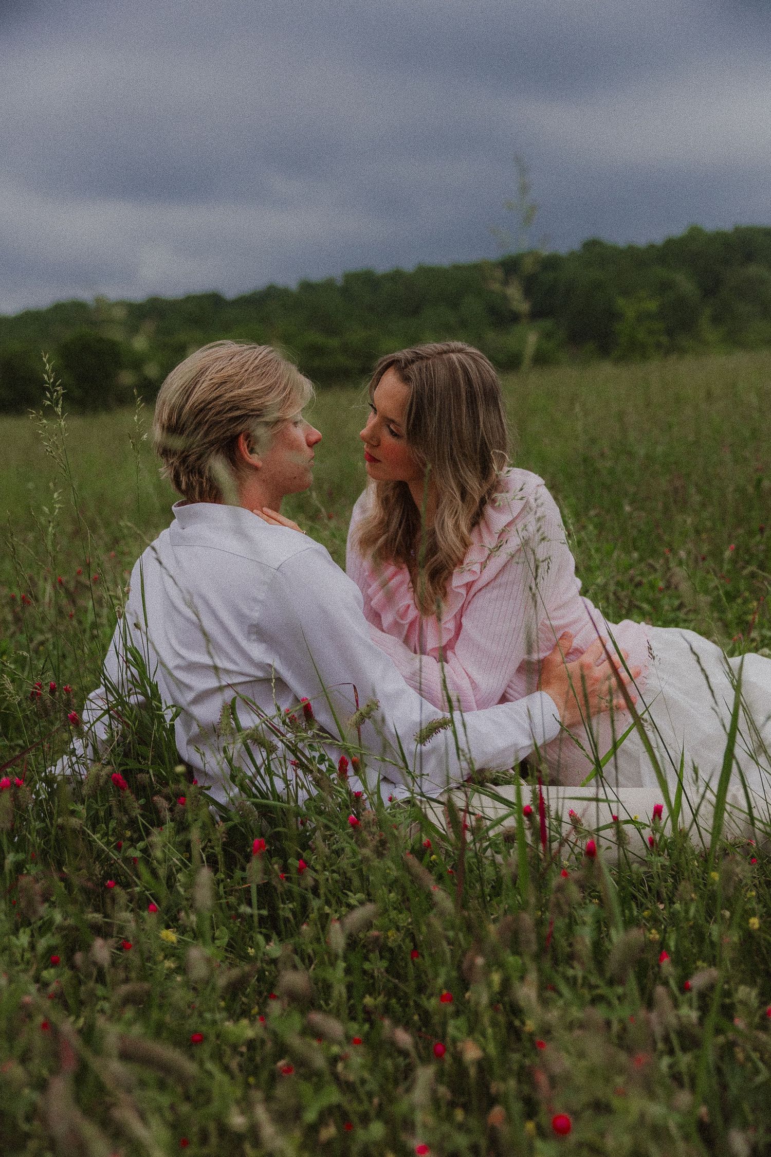 couple sitting in flower field with stormy weather