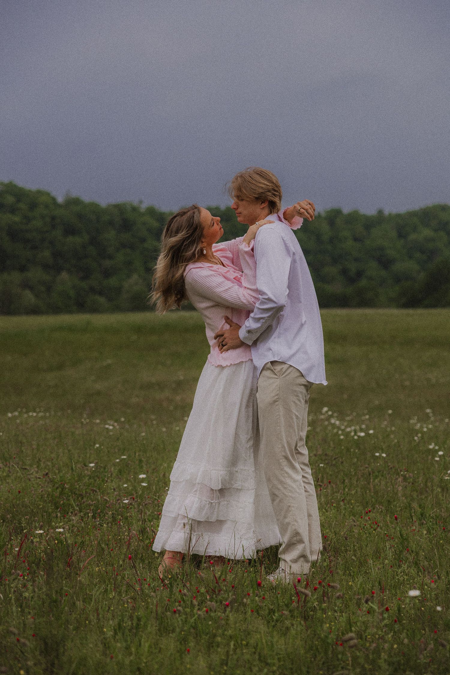couple embracing in field in stormy weather