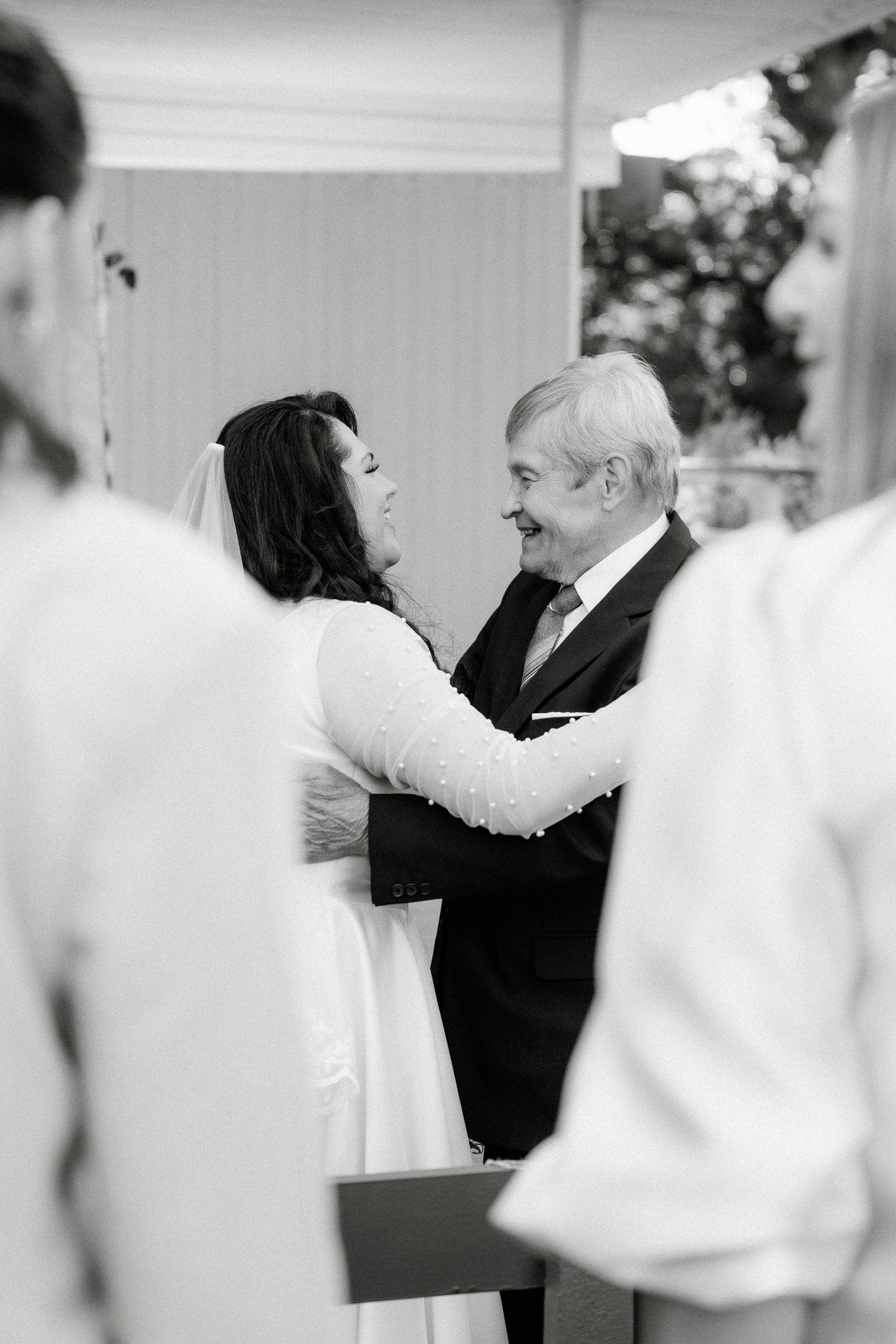 Black and white photo of a bride and groom sharing a tender moment at their wedding ceremony altar.